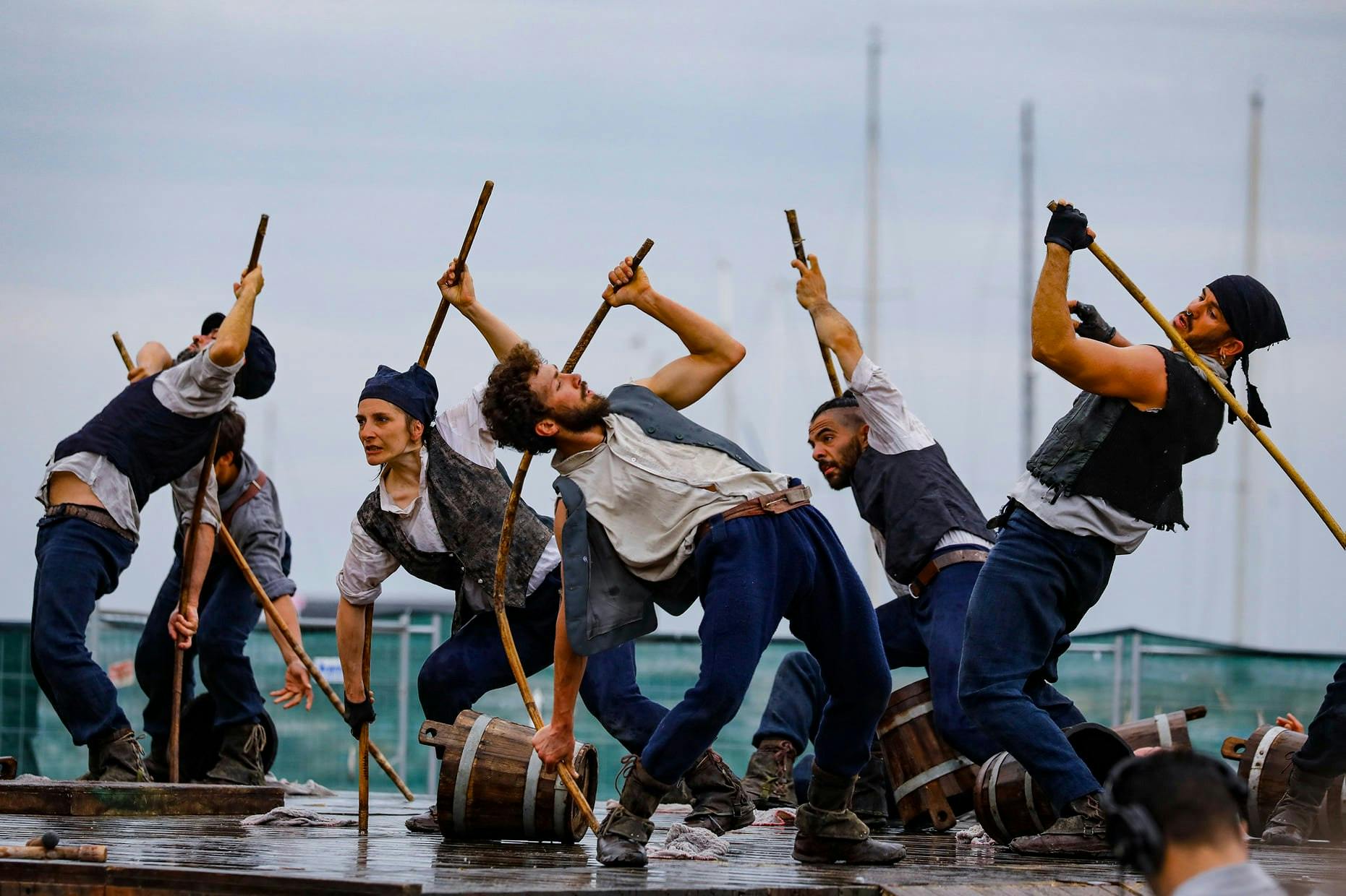 Six dancers dressed as sailors scramble with buckets and sticks in hand