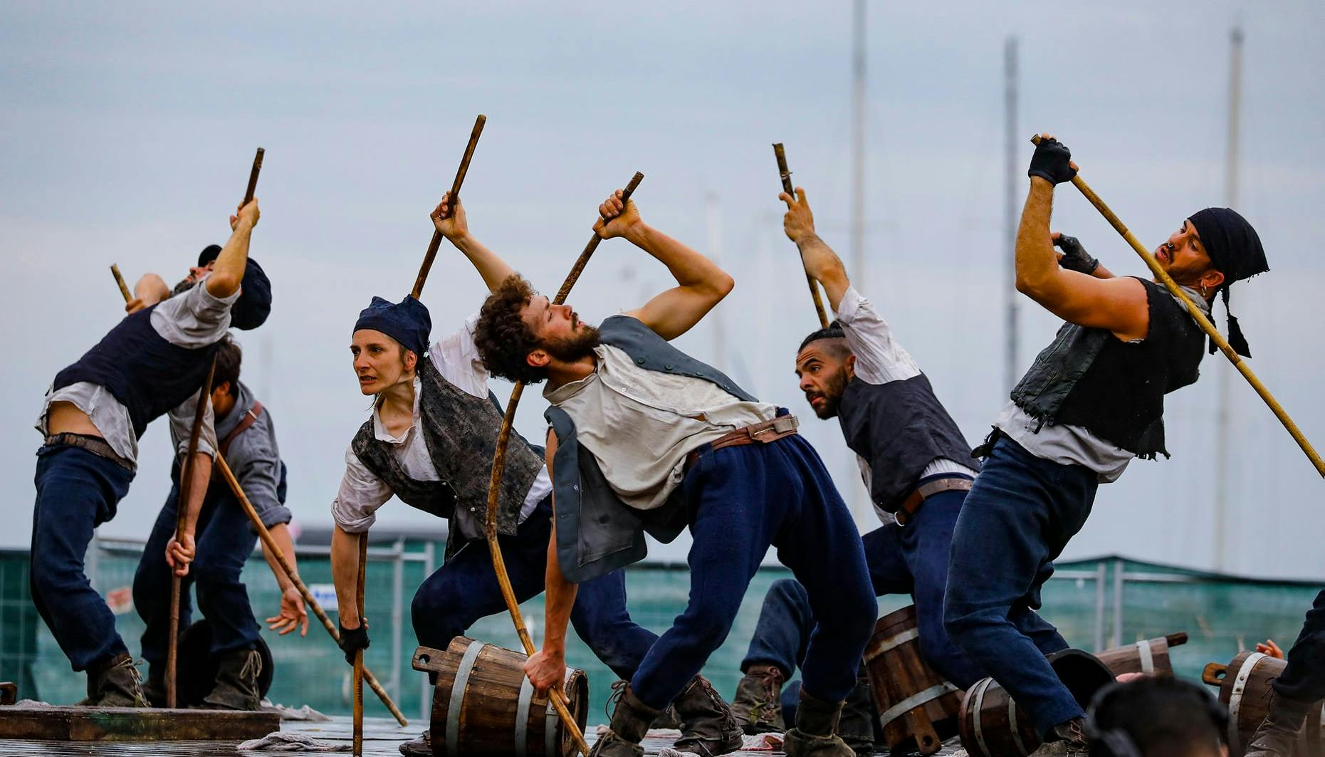 Six dancers dressed as sailors scramble with buckets and sticks in hand