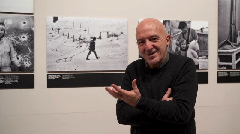 Mario Boccia in the foreground, with a photo exhibition in the background.