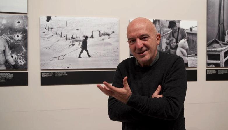 Mario Boccia in primo piano, con una mostra fotografica nello sfondo.