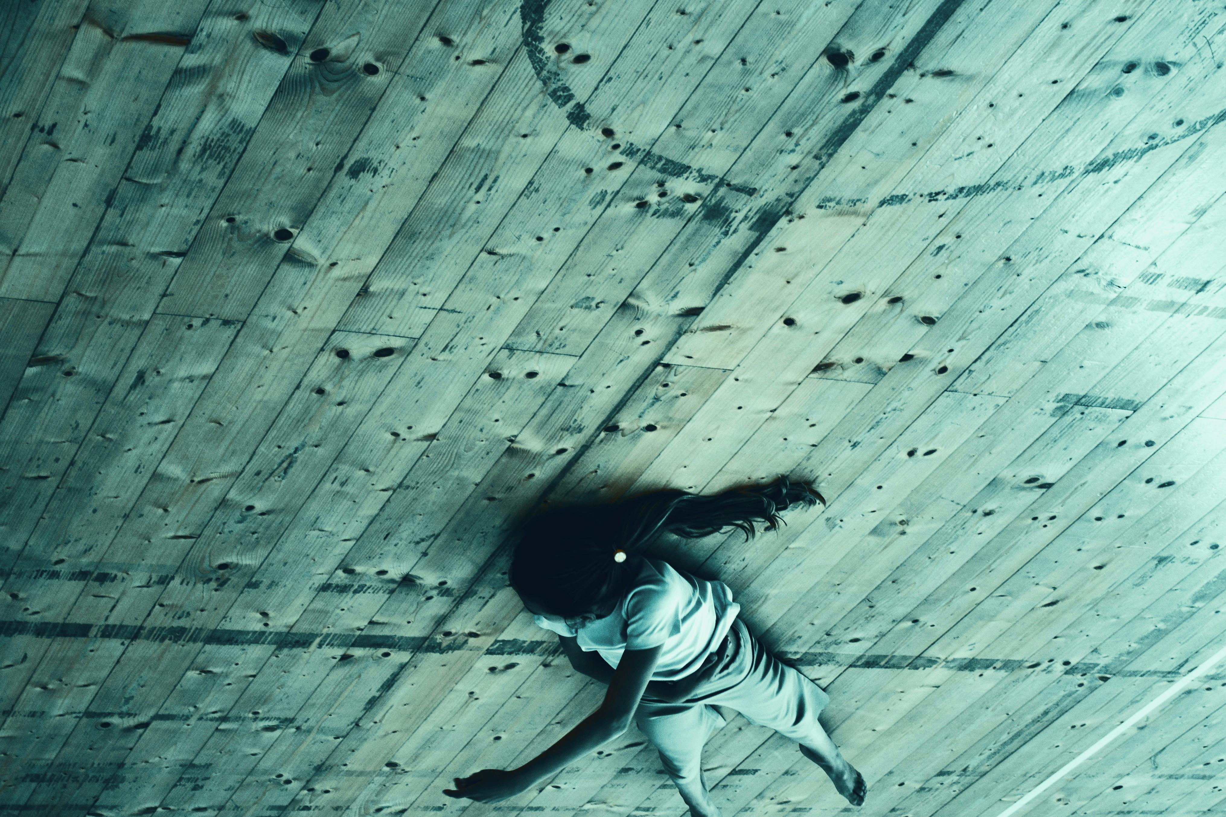 Una danzatrice sdraiata sul pavimento di legno, foto ribaltata verticalmente