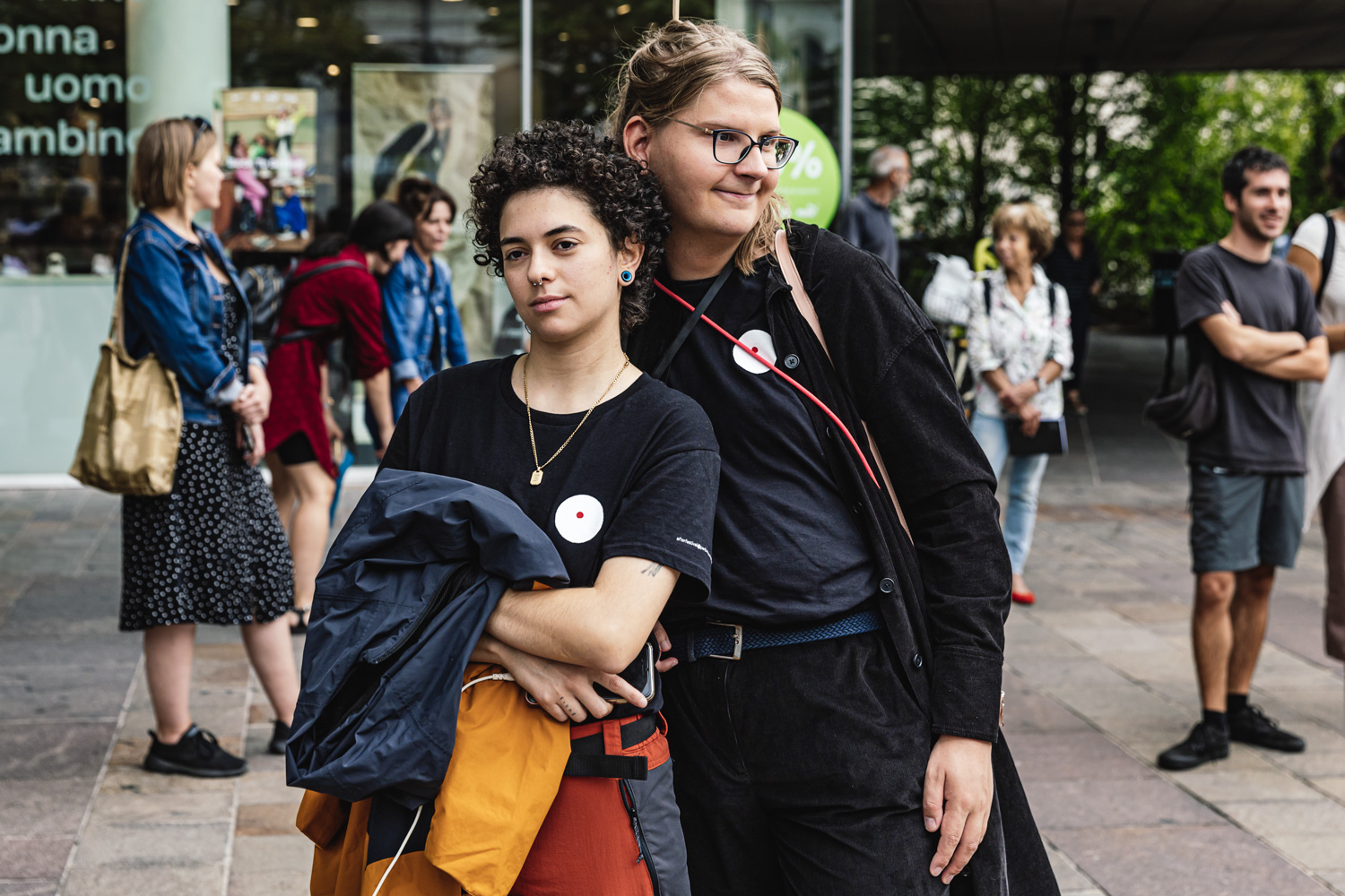 Diana Anselmo e Chris Manassero, staff di accessibilità 2023, con t-shirt nera di Oriente Occidente posano spalla contro spalla
