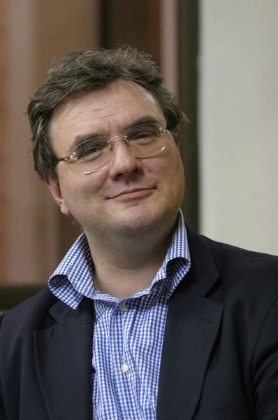 In foto Alessandro Politi, analista politico e strategico. Indossa occhiali, camicia a quadretti azzurri e bianchi e una giacca blu scuro.