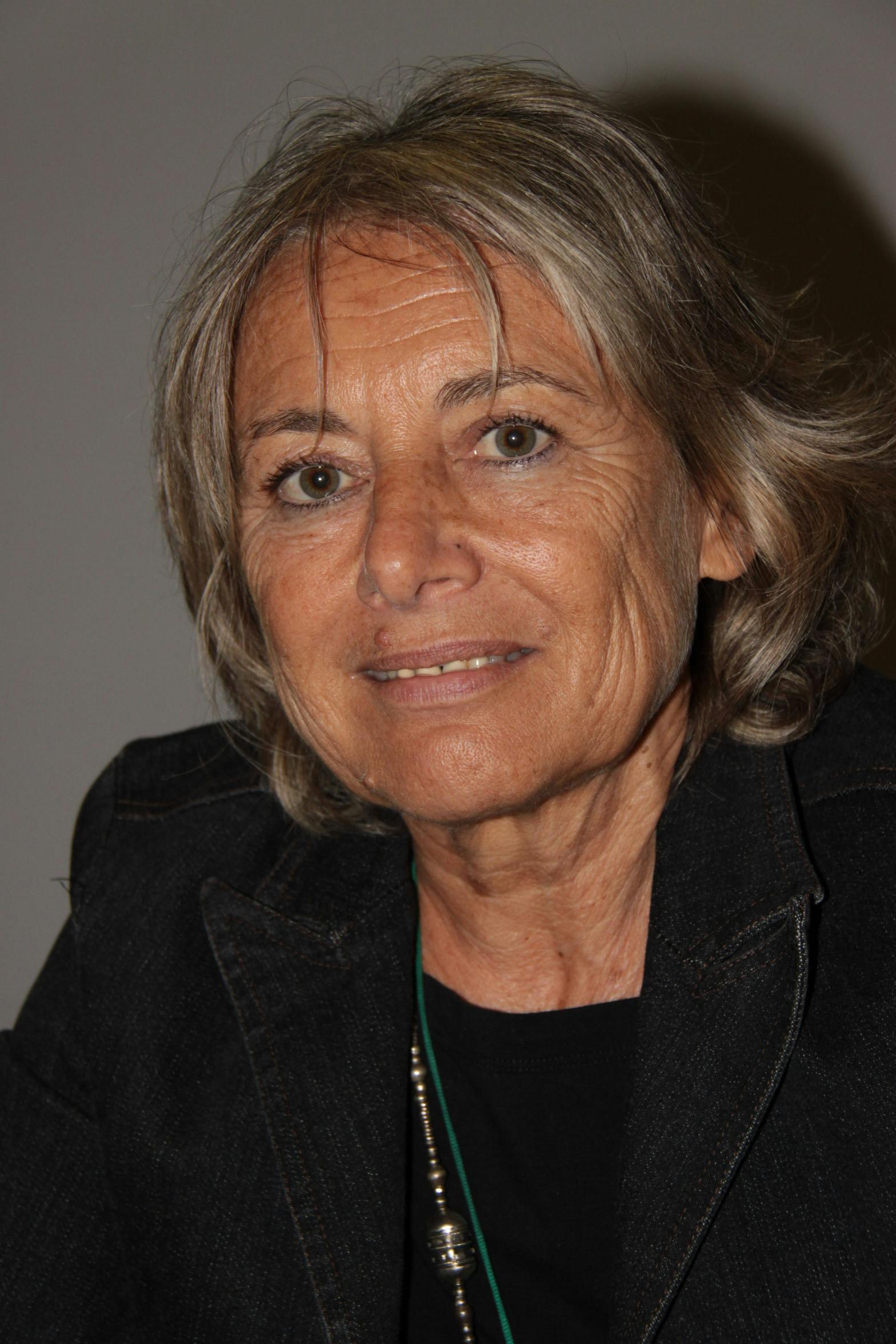 In foto, Giuliana Sgrena, giornalista de Il Manifesto nella sezione esteri e scrittrice. Sorride alla telecamera e indossa una giacca scura.