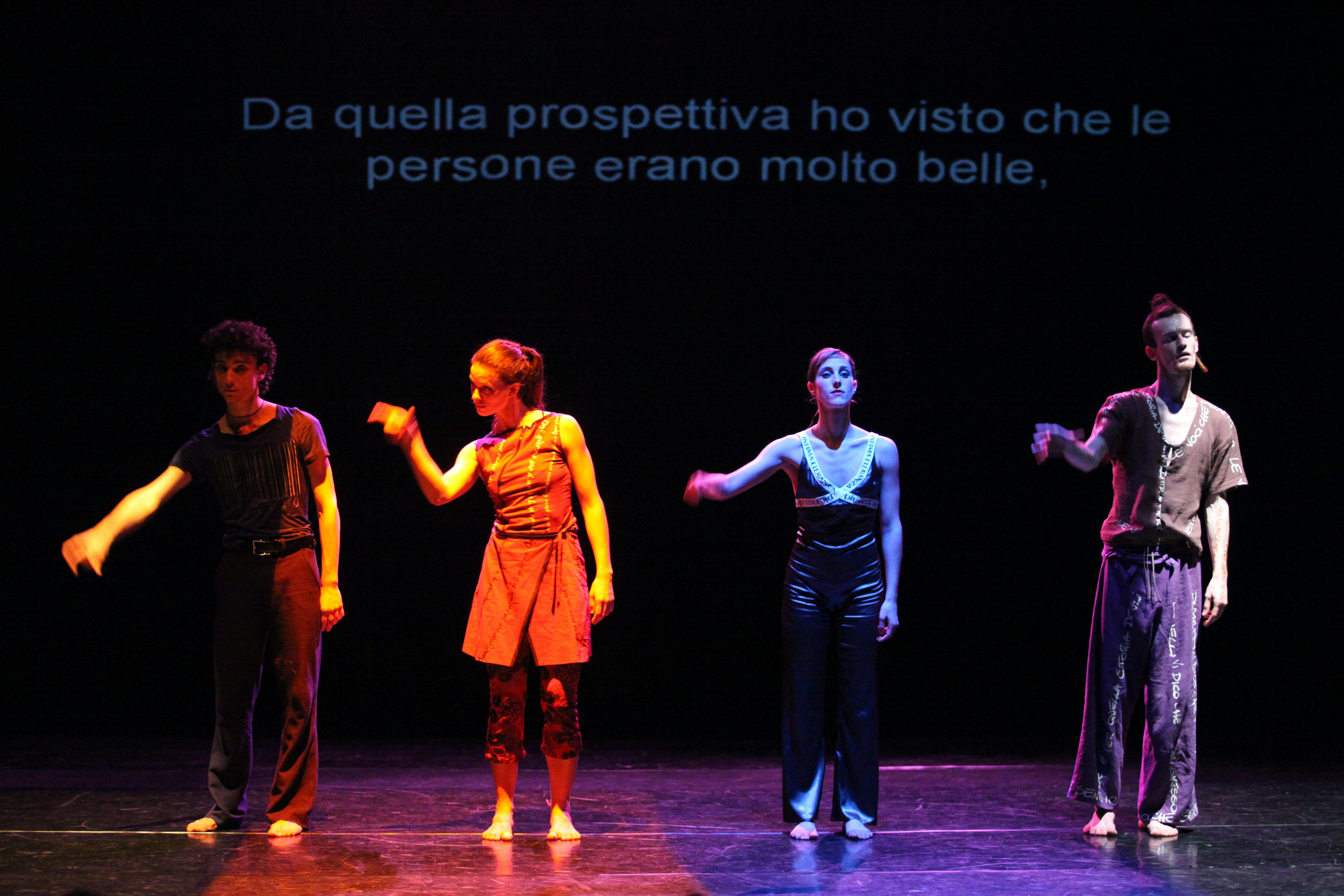 Quattro artisti, uno affianco all'altro. Hanno la mano destra alzata. Dietro di loro è proiettata la scritta: "Da quella prospettiva ho visto che le persone erano molto belle"