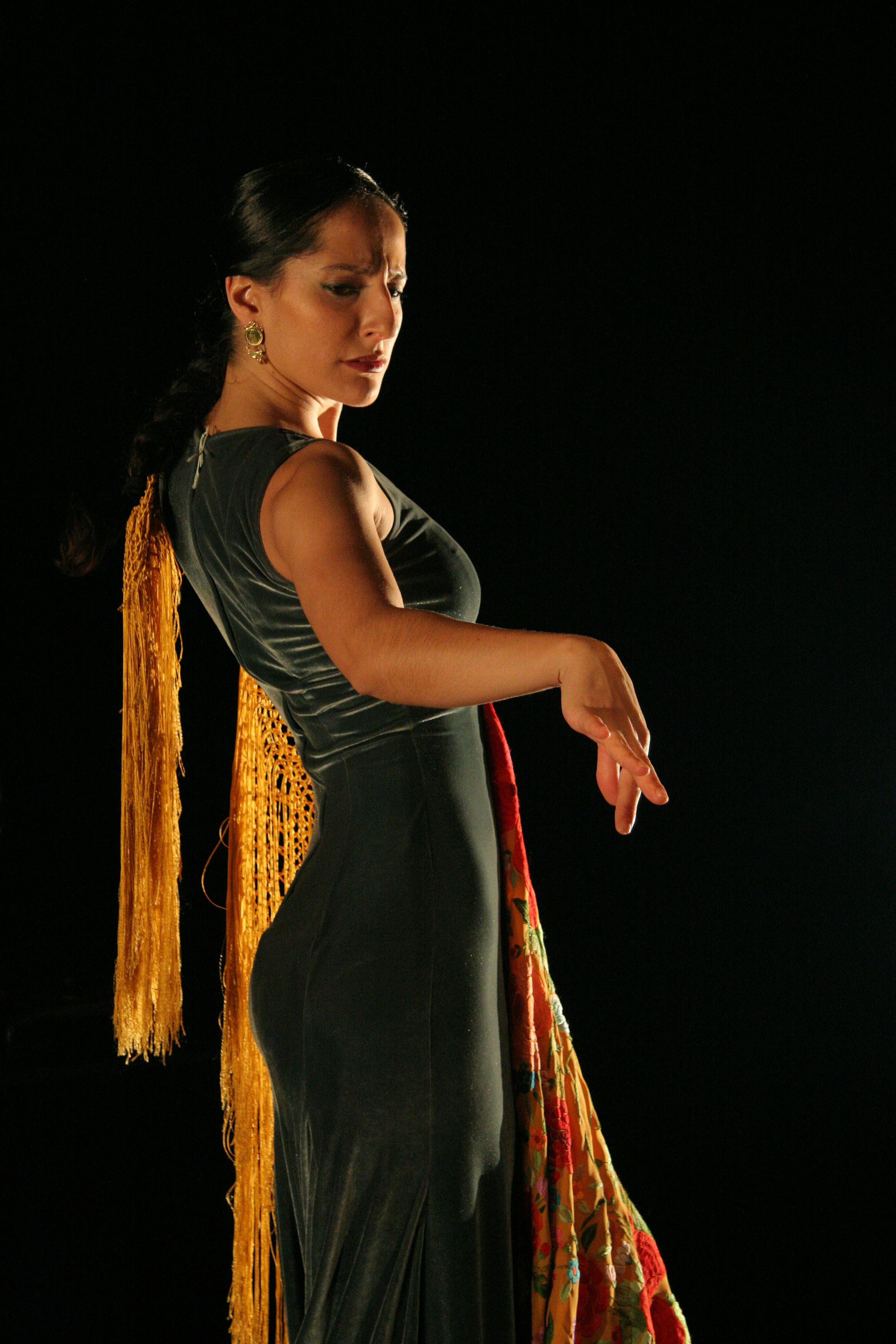 Profile picture of a ballerina. She is standing, her right arm stretched out to the side. She is wearing a long, green velvet dress.