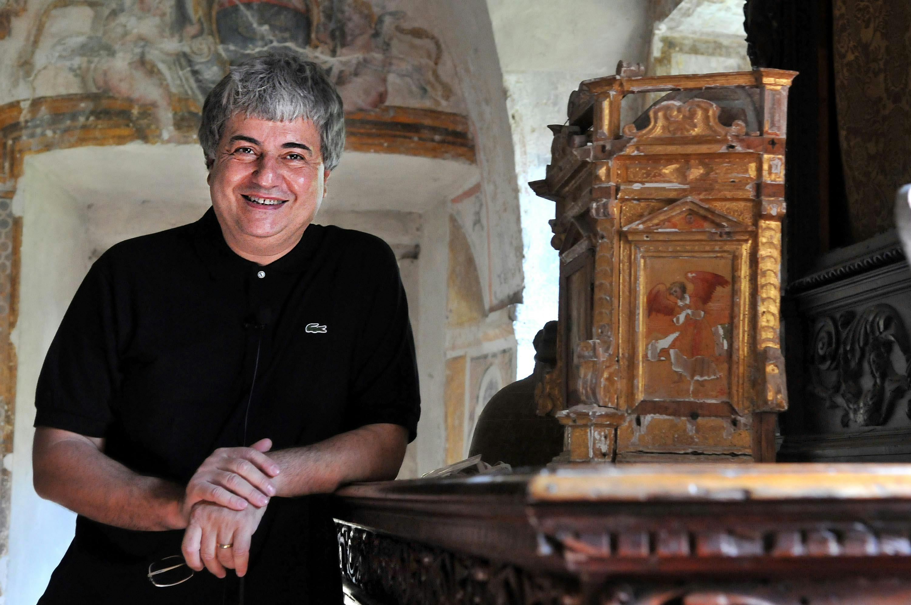 In the foreground, Ermete Realacci is leaning against an altar. He has white hair and is wearing a black polo shirt.