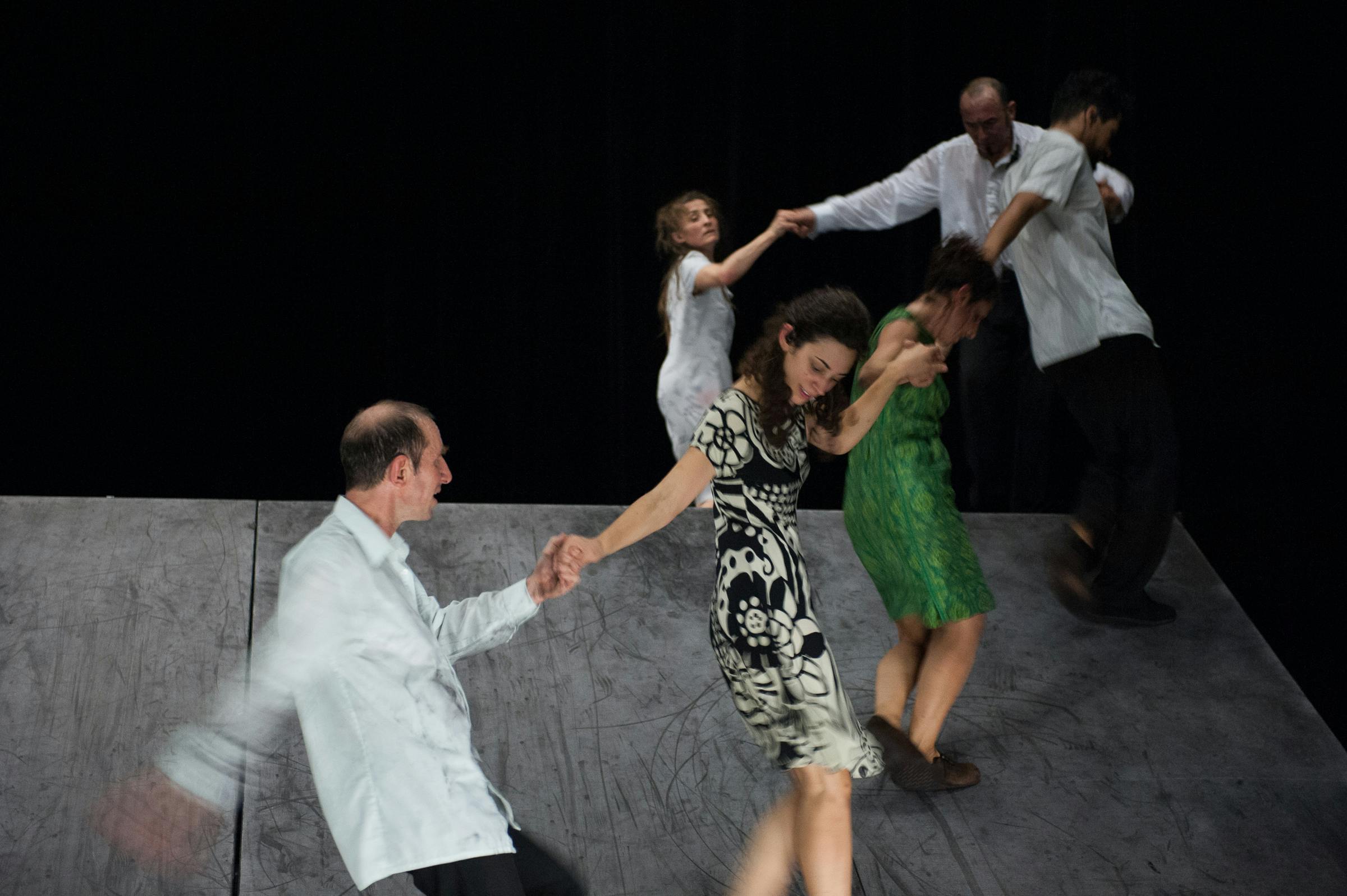 Six artists on stage, blurred. They move while holding hands.