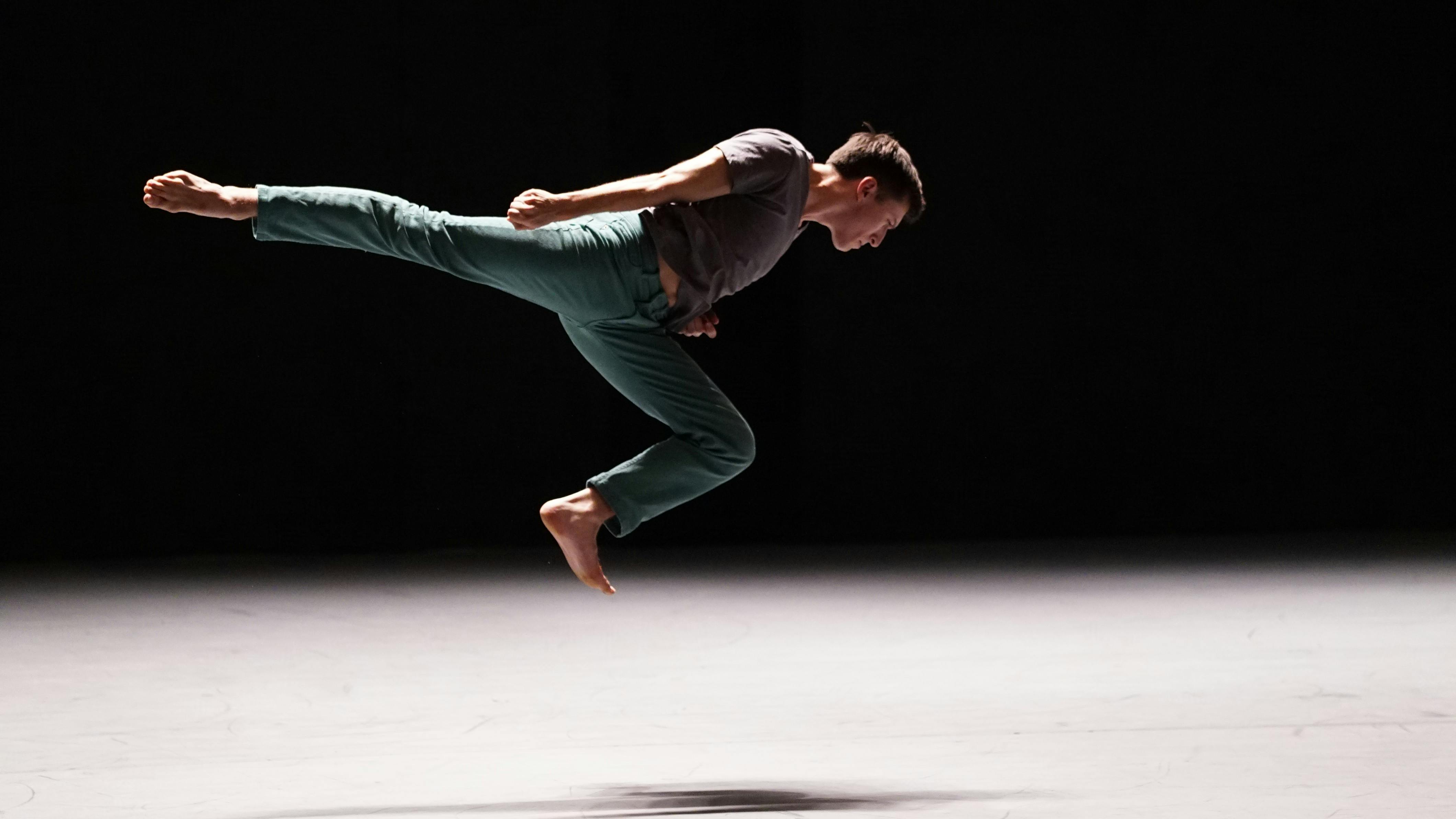 A person is in mid-air, horizontally. They have their right leg extended back and their left leg bent.