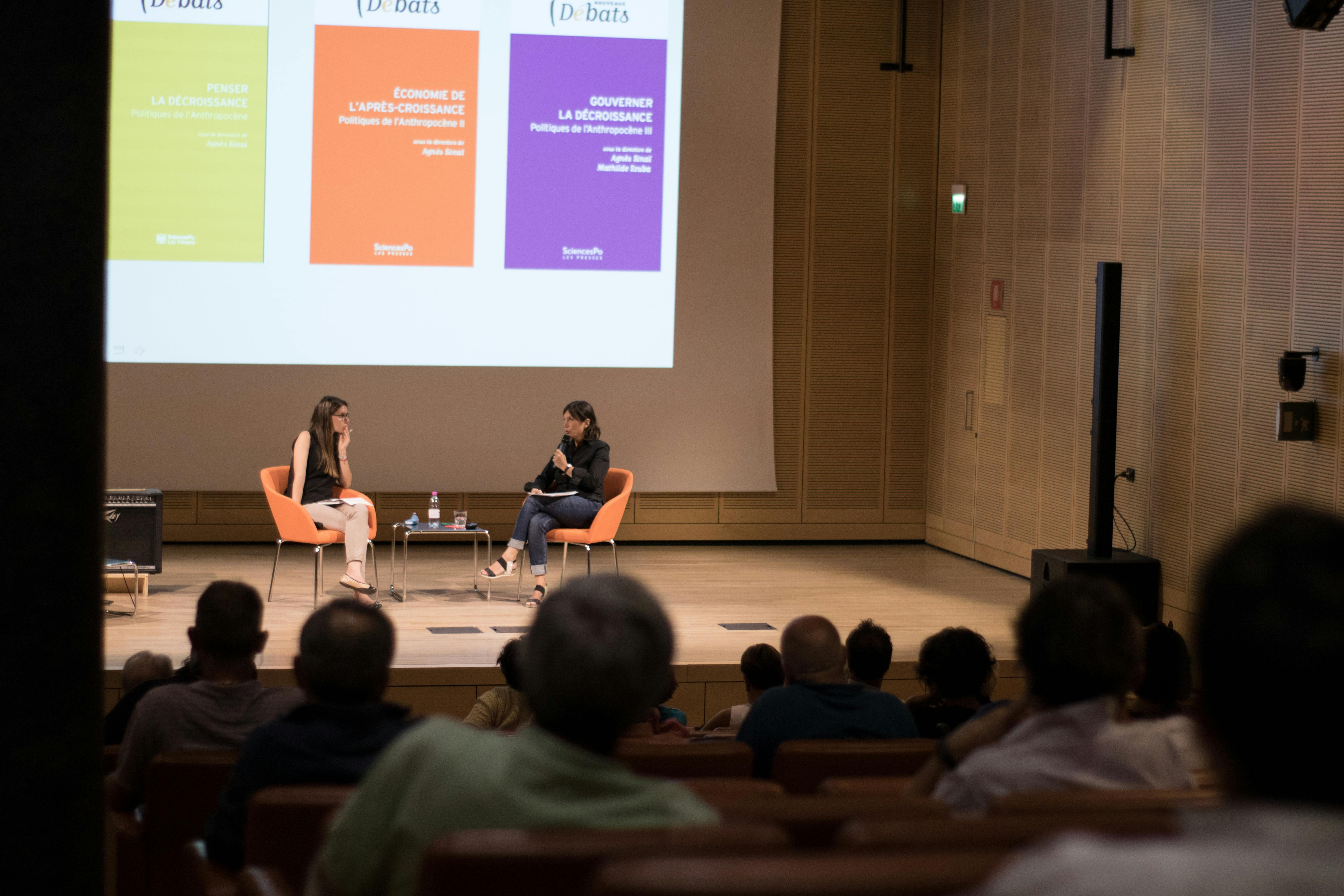 Agnès Sinaï, an environmental journalist, on stage speaking in front of an audience. Another woman is on stage with her.