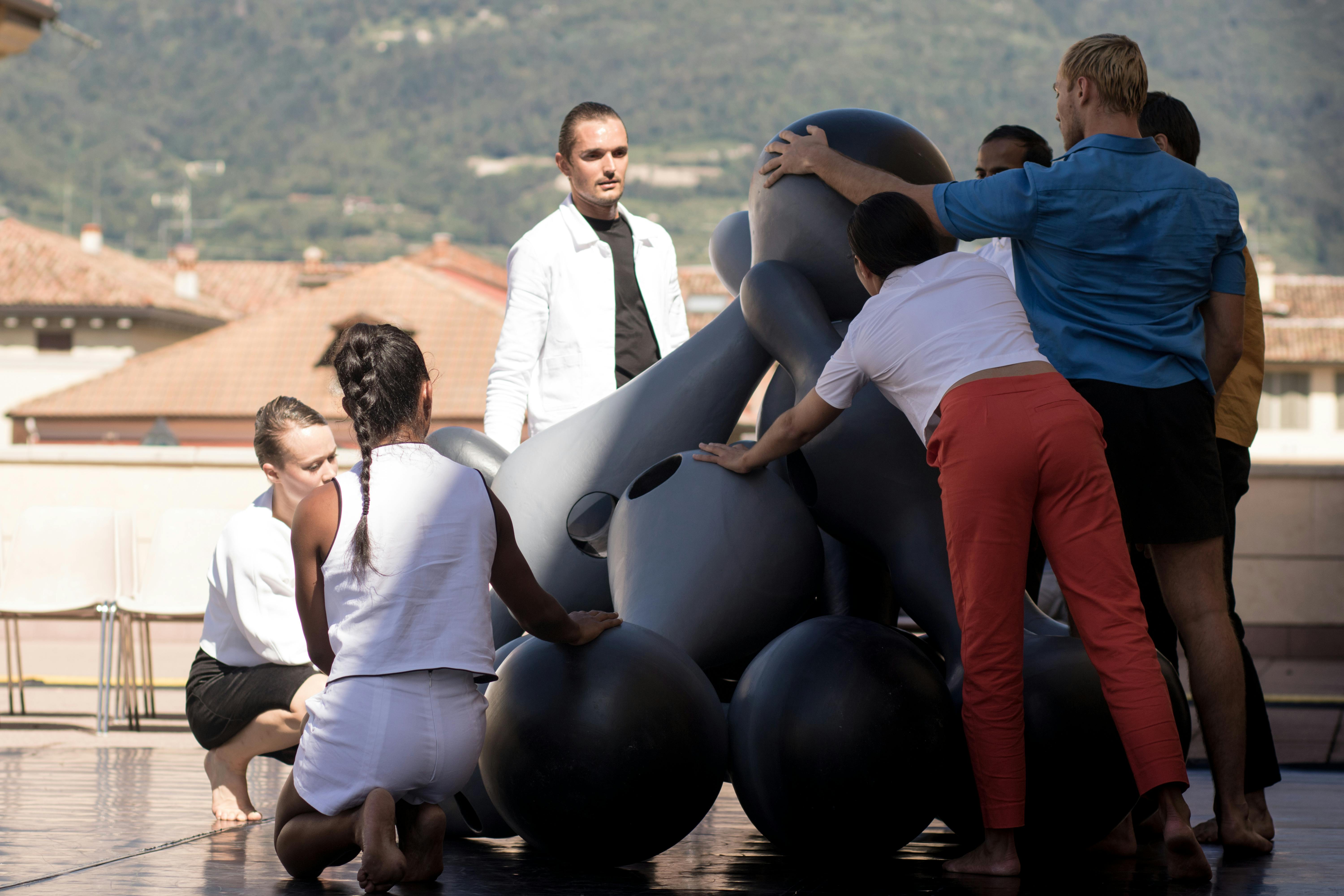 Sette artisti in scena sulla terrazza del MART. Toccano e guardano delle sculture a forma di birillo a grandezza umana