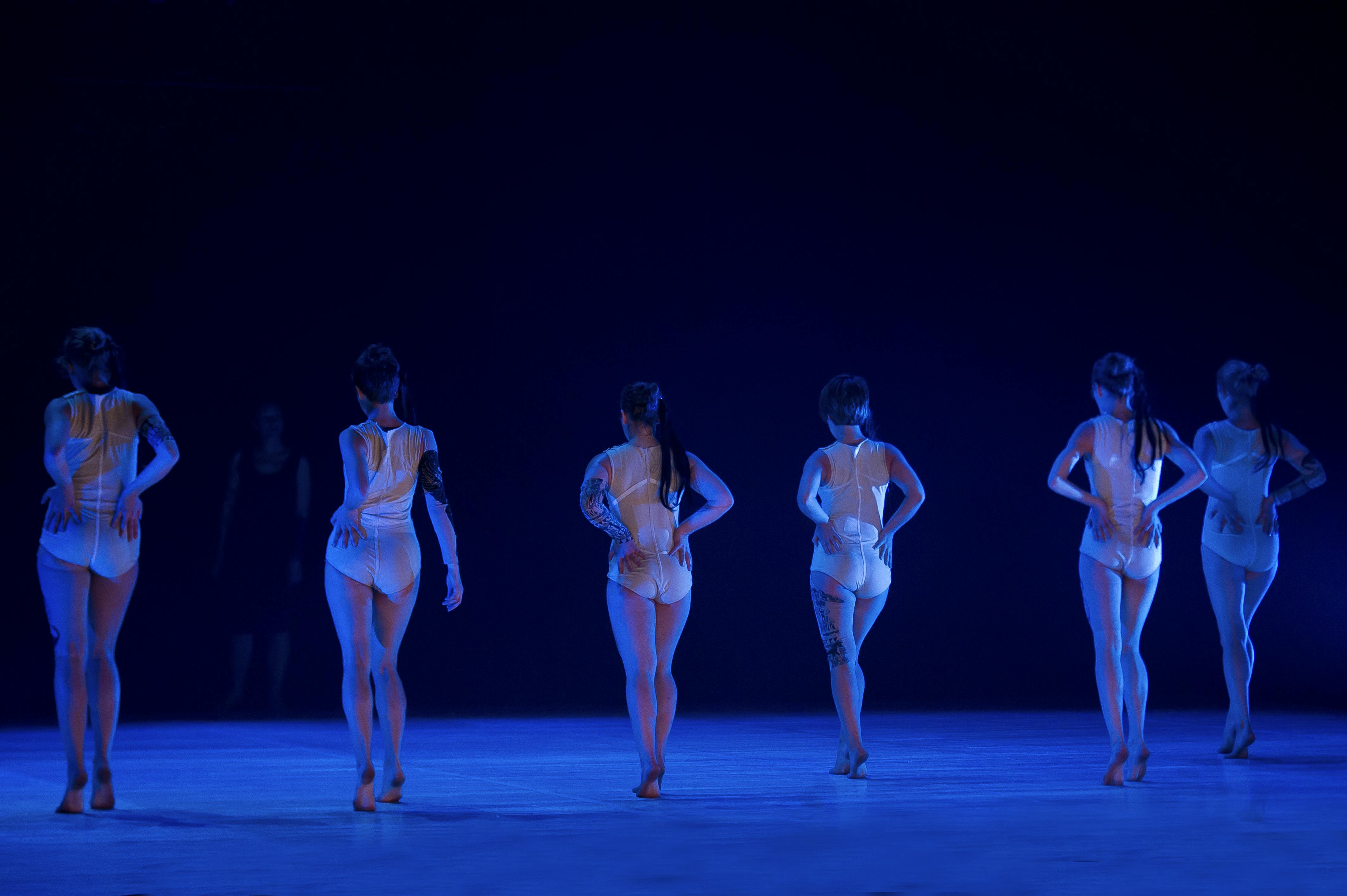 Sei ballerine di spalle. Sono una accanto all'altra. Indossano body bianchi.