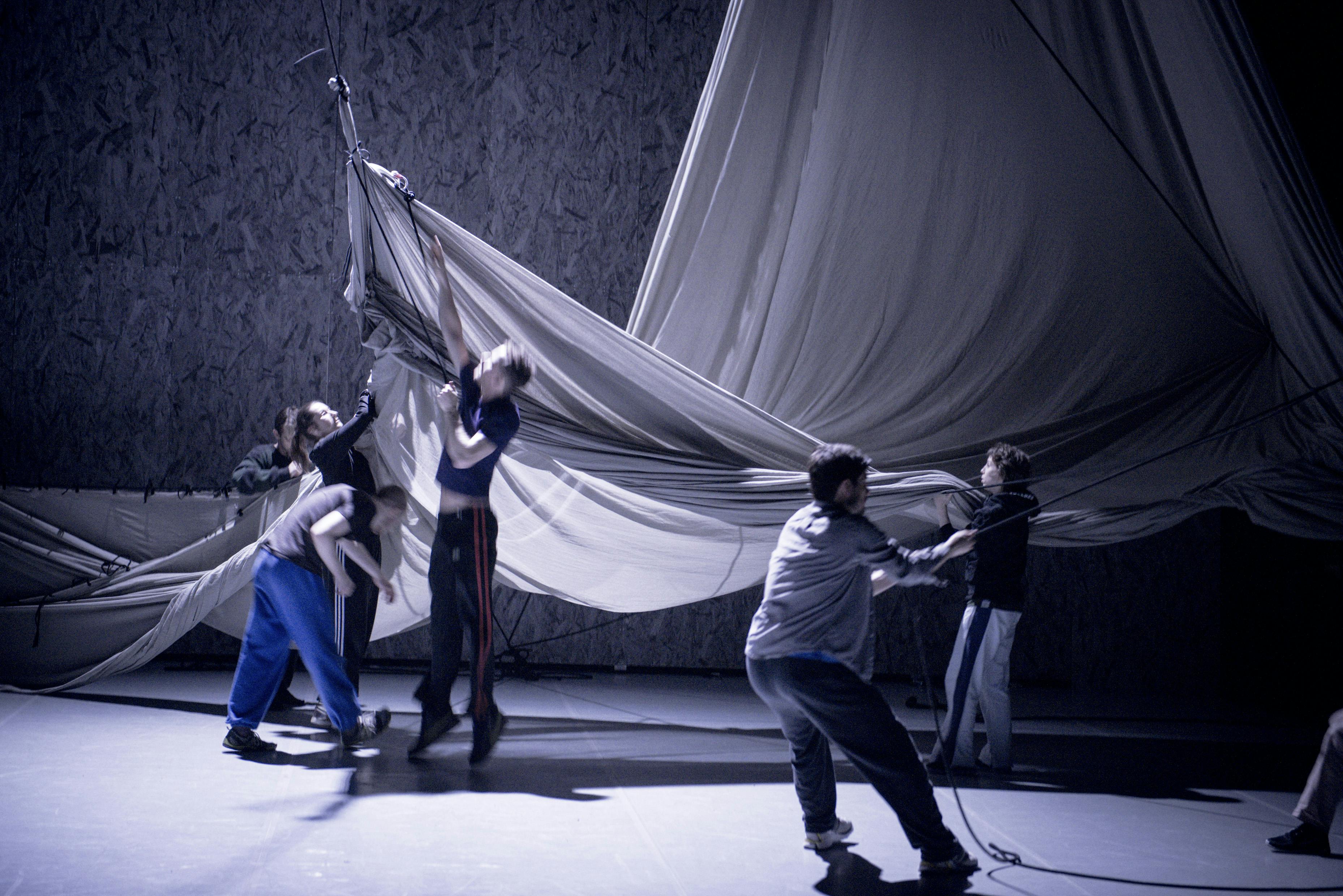 Five artists on stage. They are clinging to very large fabrics.