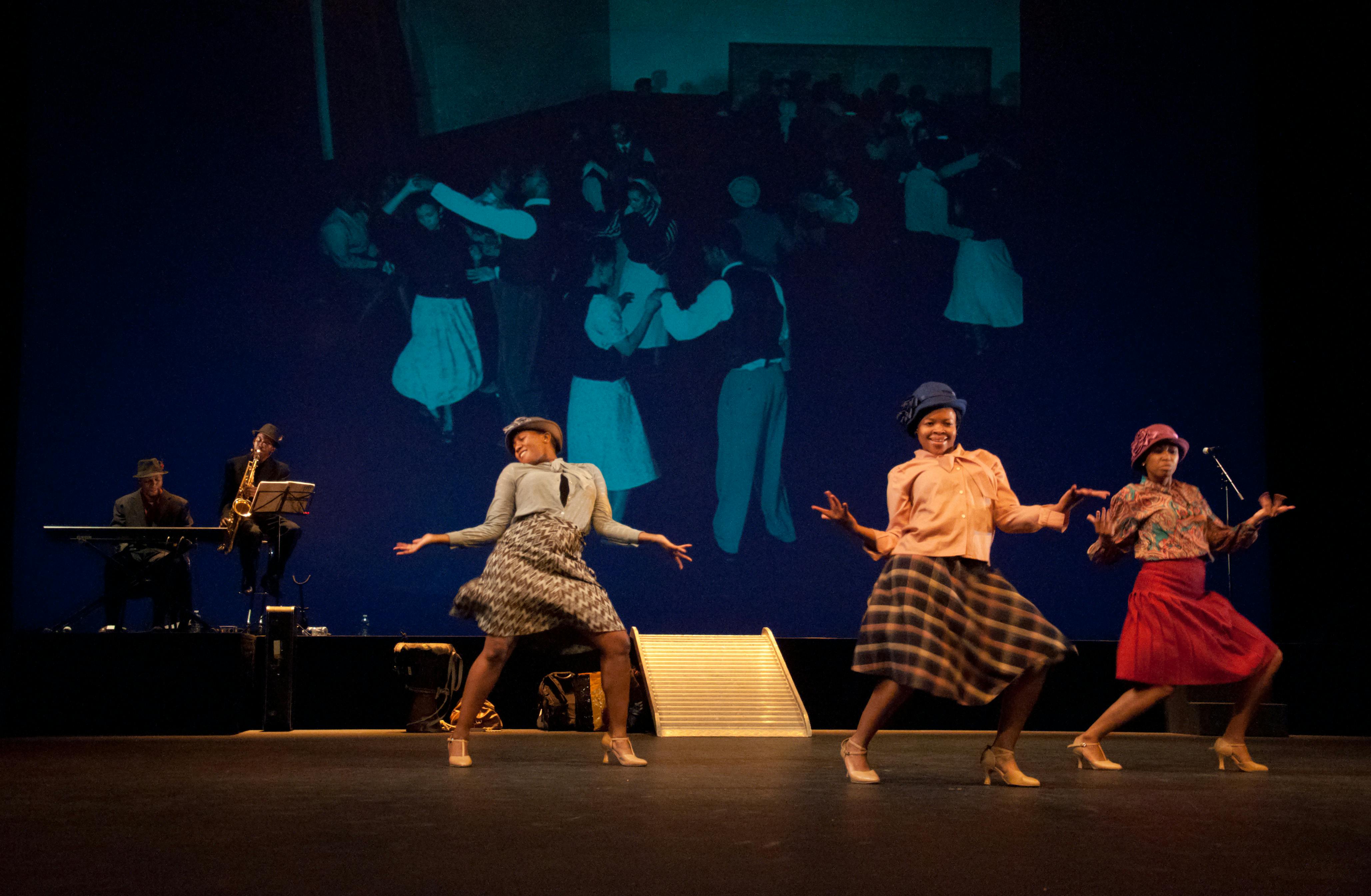 Tre ballerine in scena, hanno abiti anni '50. Dietro di loro un tastierista e un sassofonista