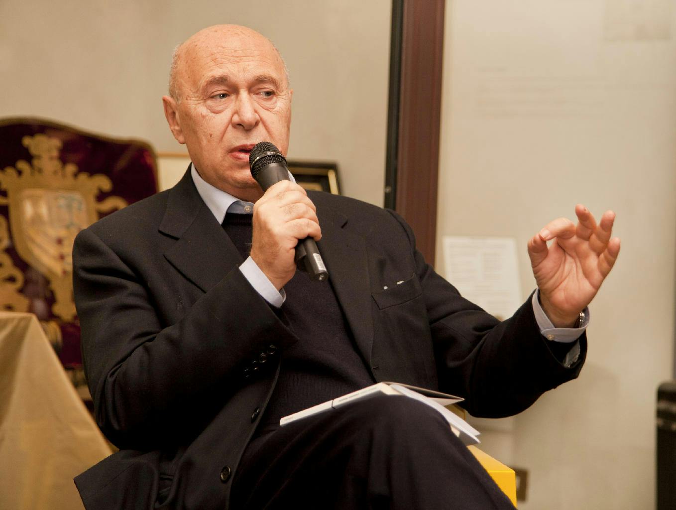 in foto Paolo Mieli, giornalista e scrittore, mentre parla al microfono. Indossa un completo scuro.
