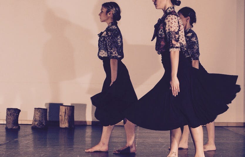 Three ballerinas, standing in profile. They are walking seriously in front of them, wearing wide black skirts.