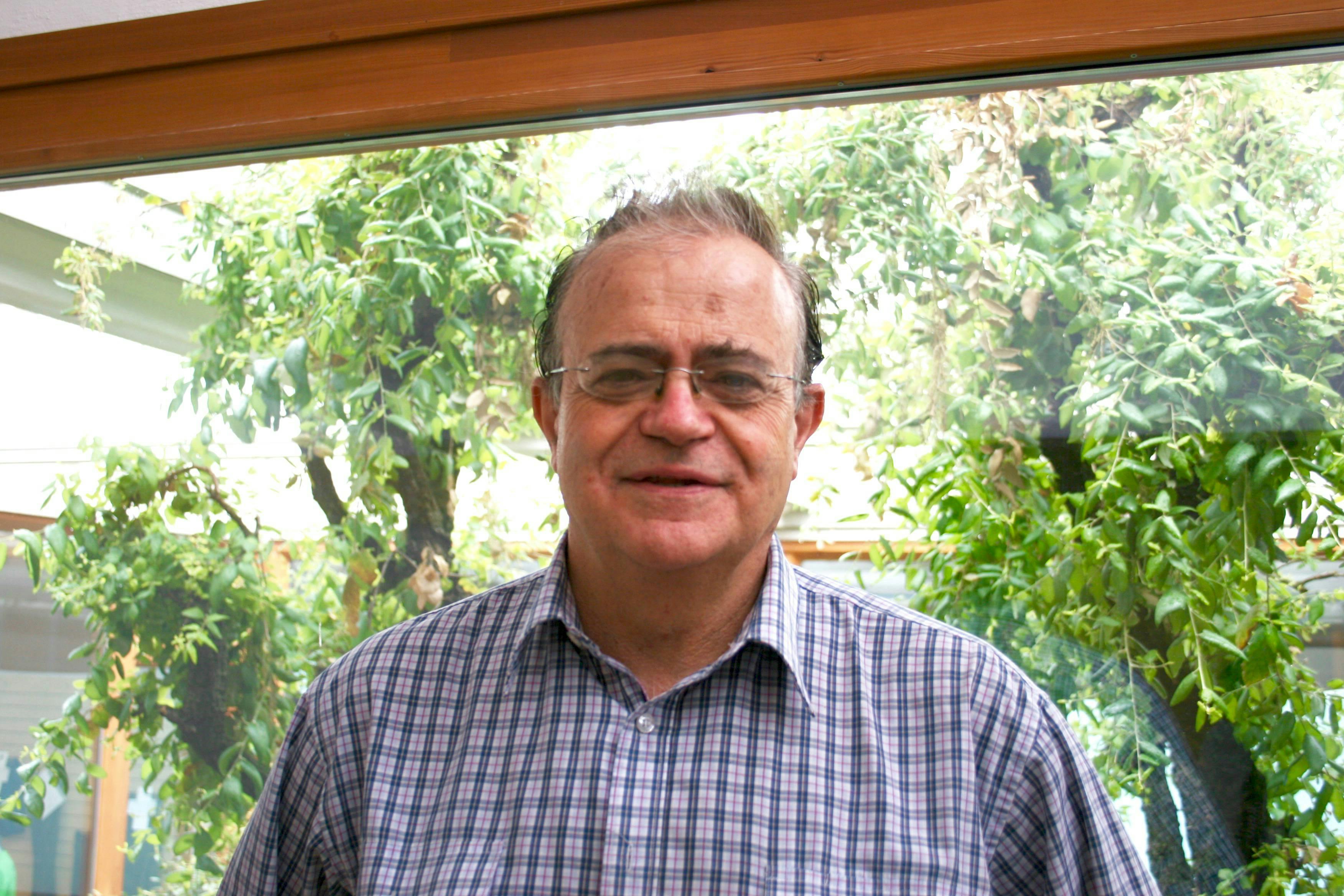 Ritratto di David Bellatalla, antropologo. Sorride alla telecamera, indossa una camicia a quadretti.