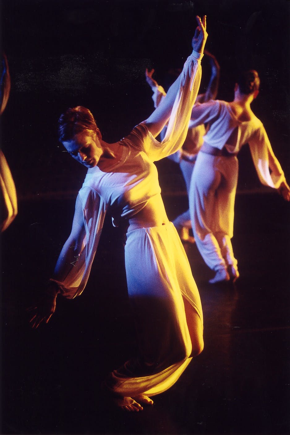 Three dancers move through space wearing draped robes