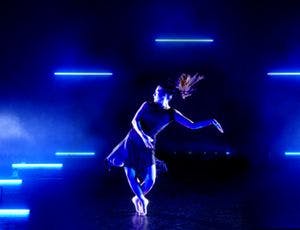 Ballerina dancing with blue lights around her.