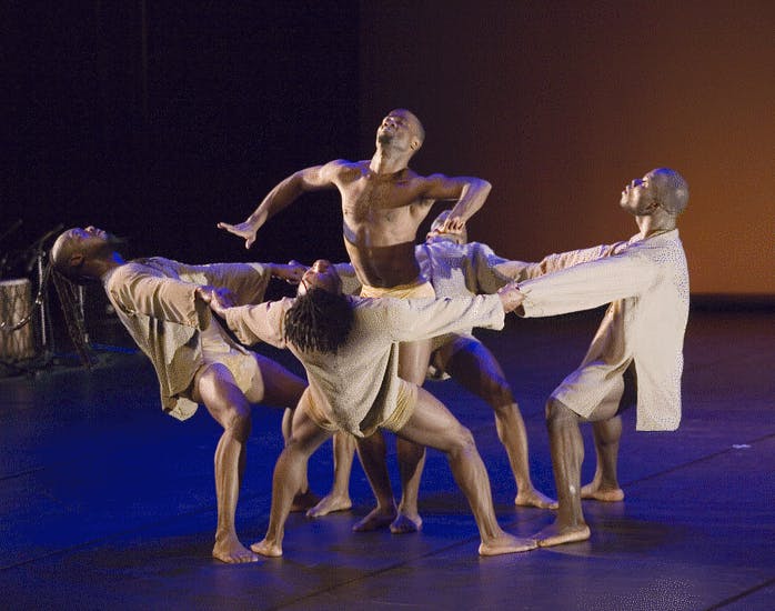 Cinque artisti in scena. Quattro puntano i piedi a terra e si tengono in equilibrio tenendosi per mano in cerchio. In mezzo a loro un artista a petto nudo salta.