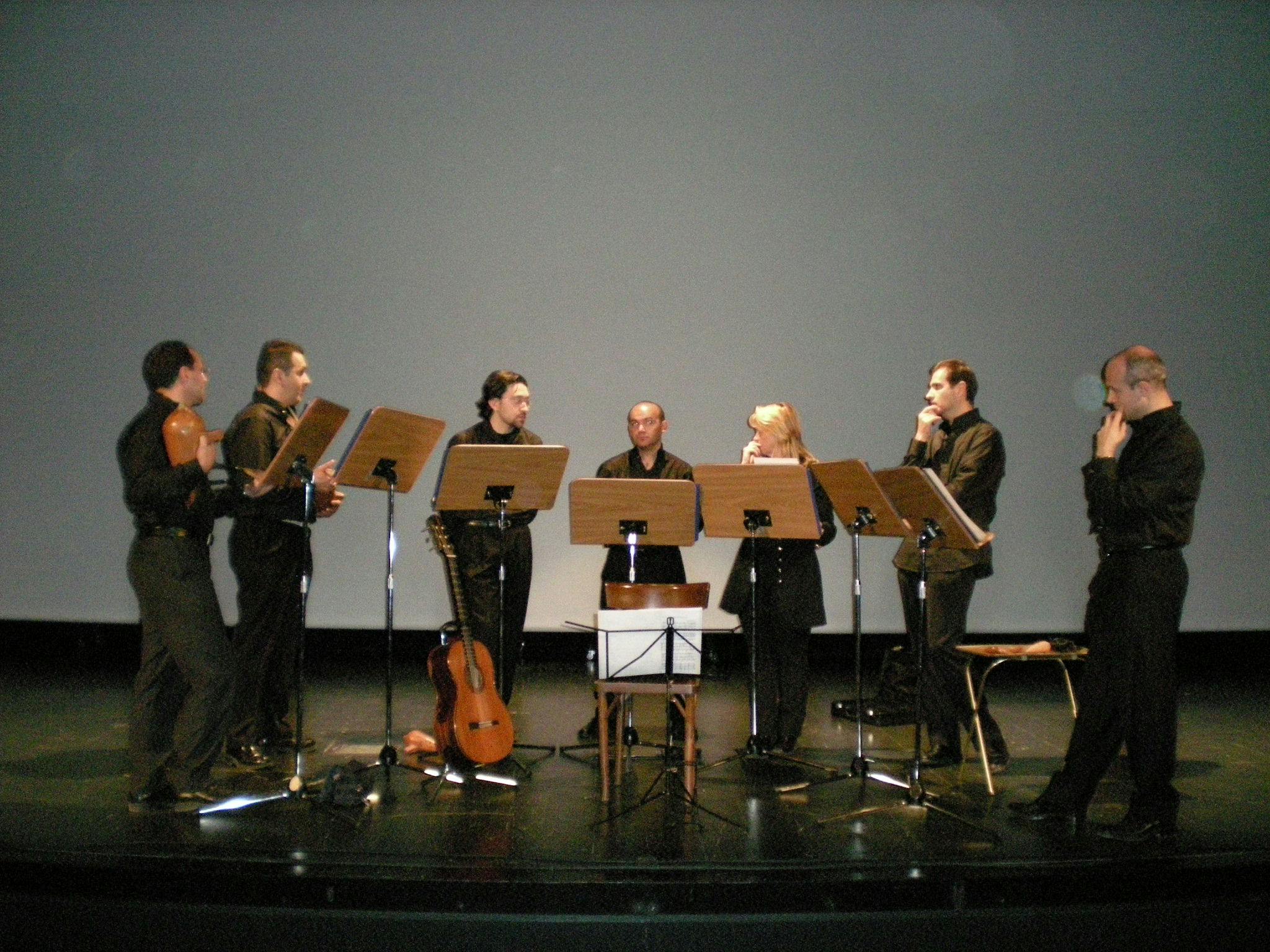 Sette musicisti davanti ai leggii suonano gli strumenti