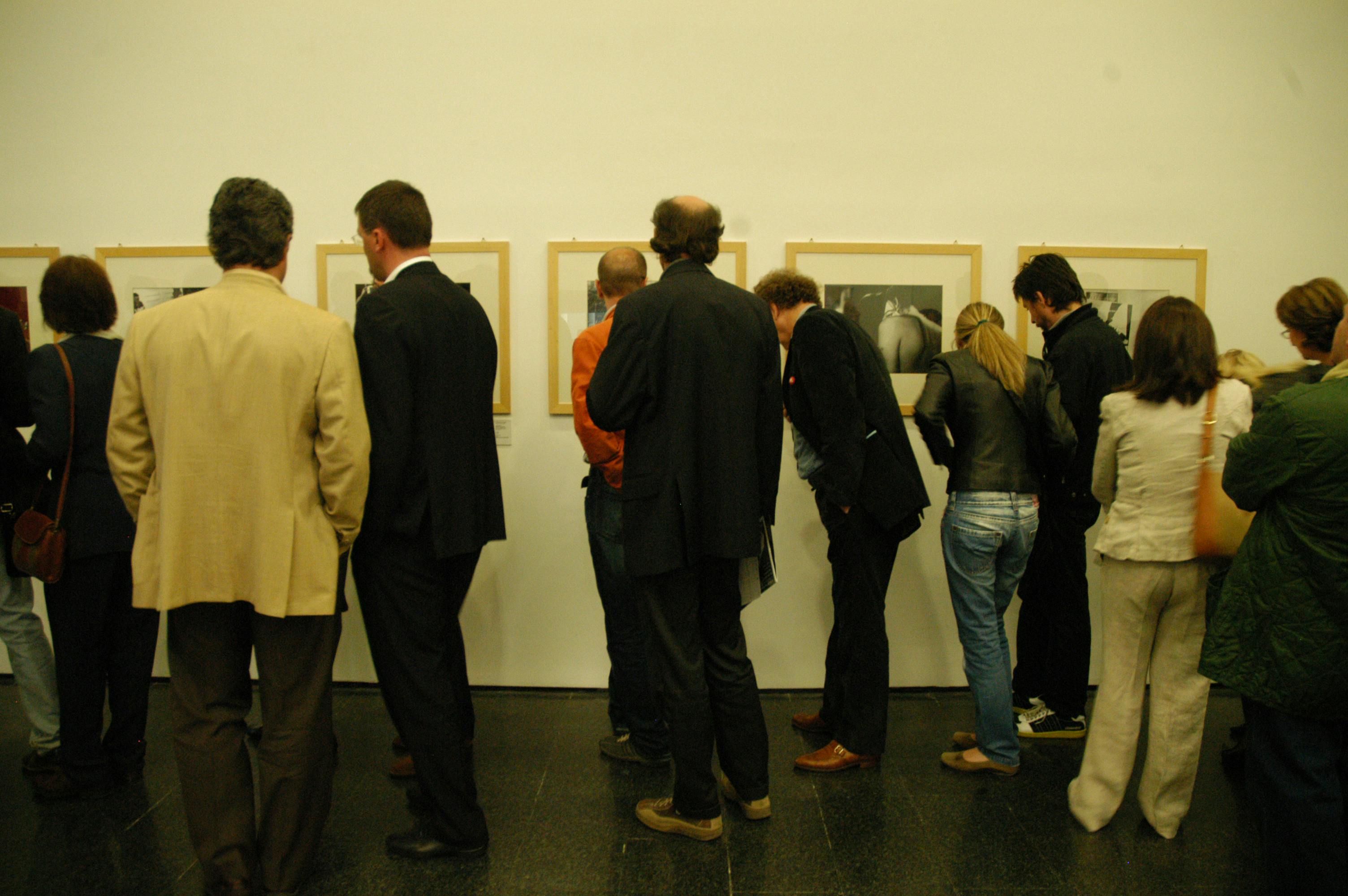 Pubblico in mostra che osserva le opere appese al muro