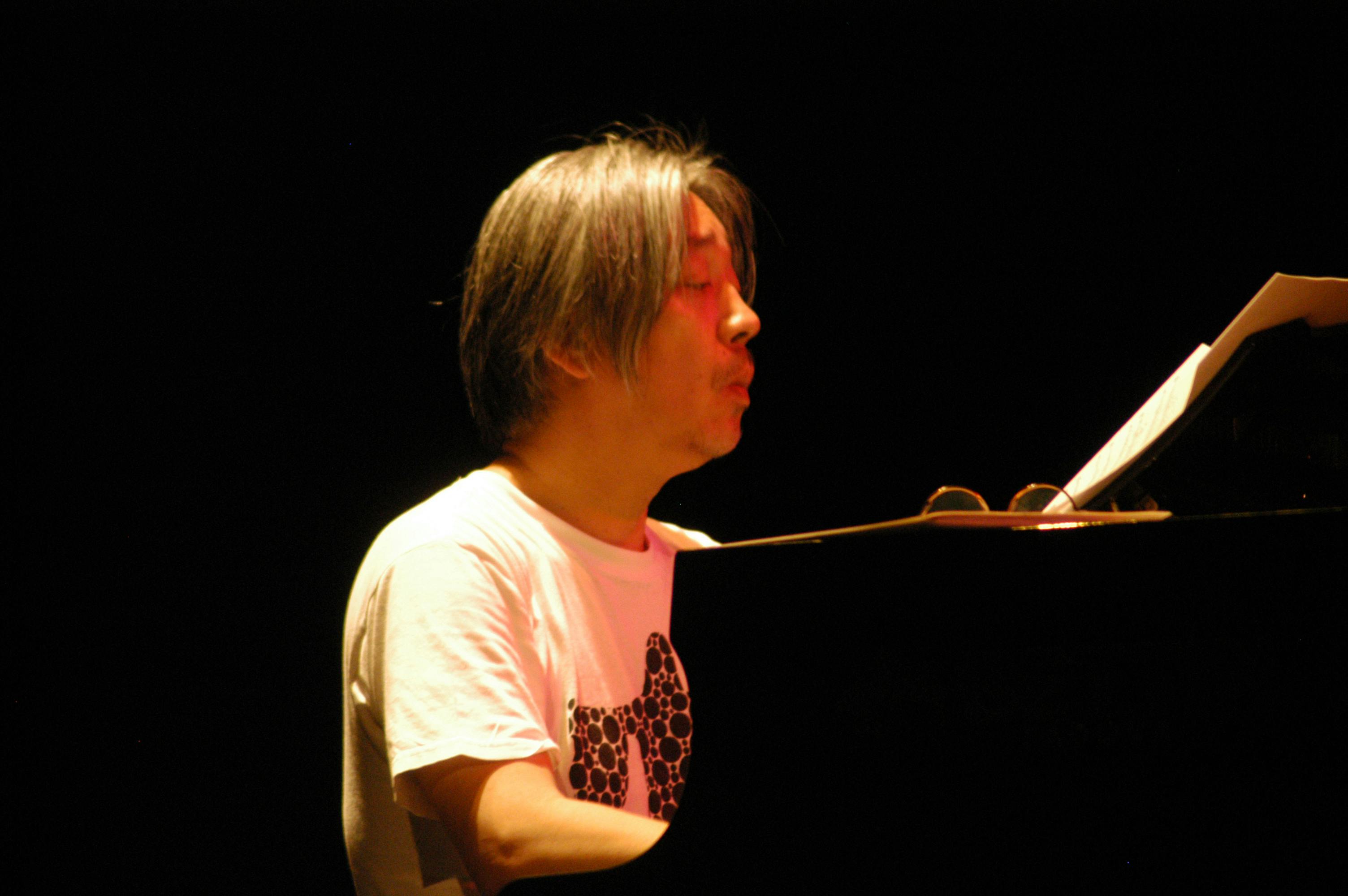 Ryuichi Sakamoto sitting at the piano
