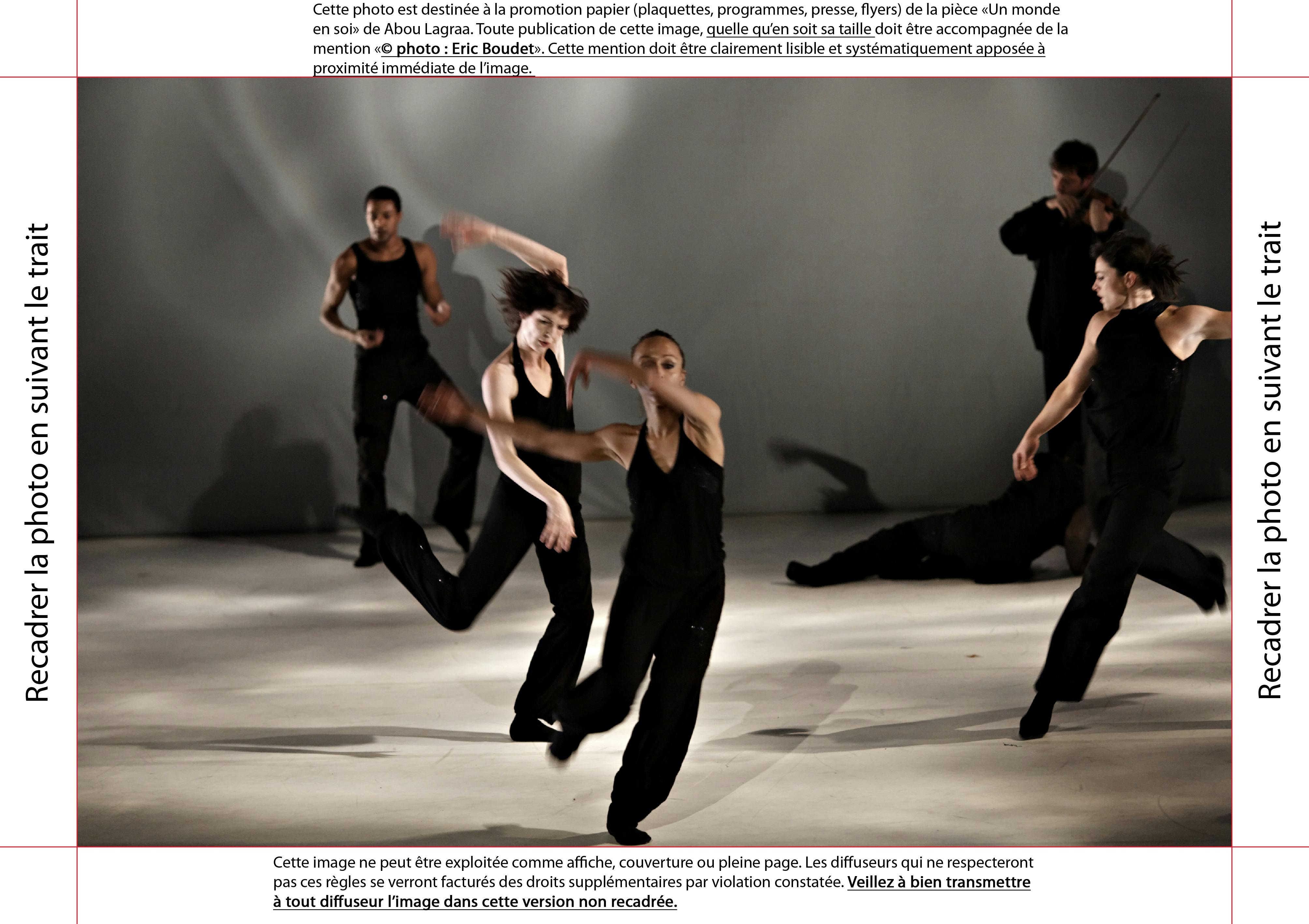 Six artists are on stage, dressed in black tank tops and pants. They are standing and moving, each in different poses.