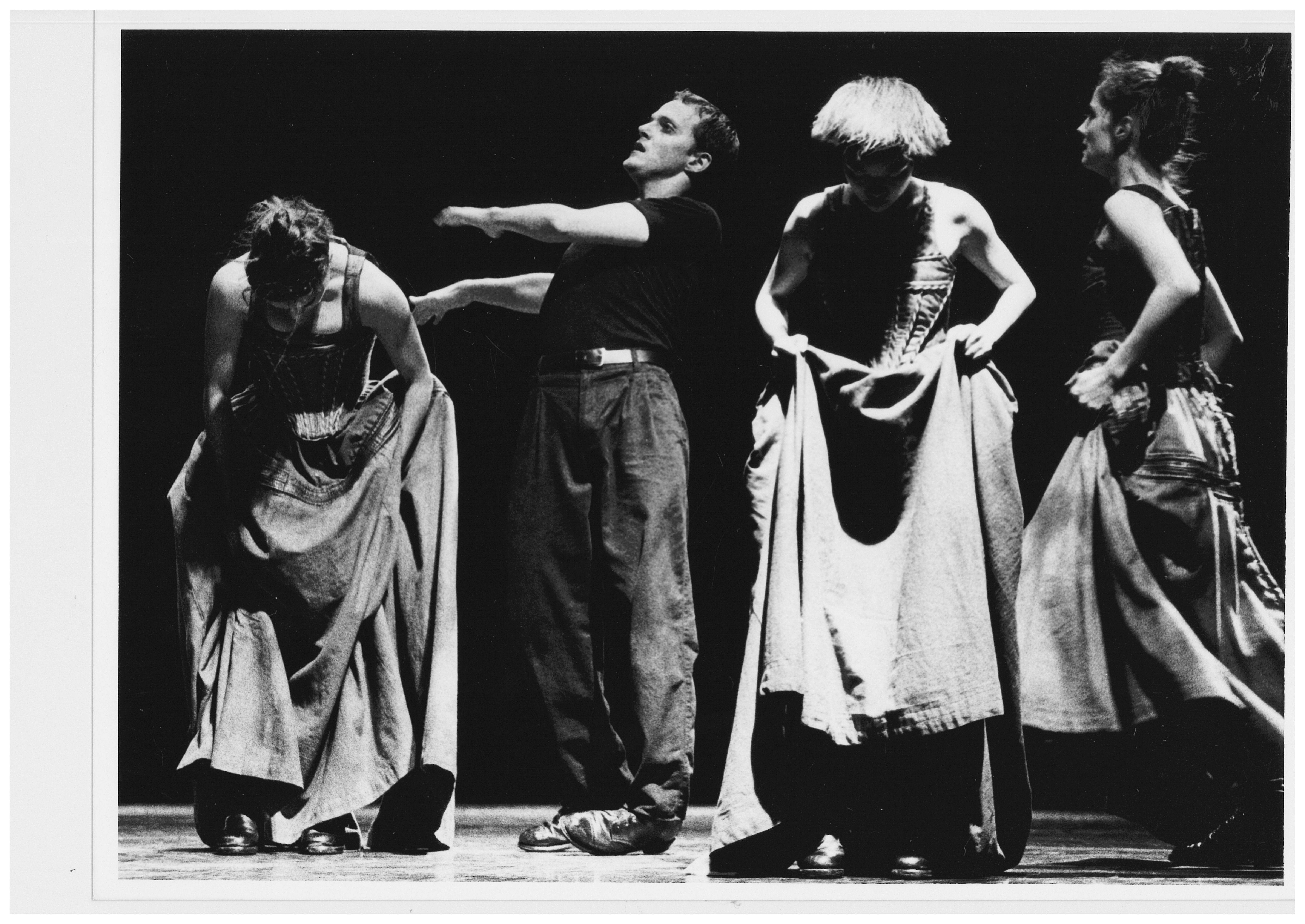 Four people standing, three women in long dresses and one man.