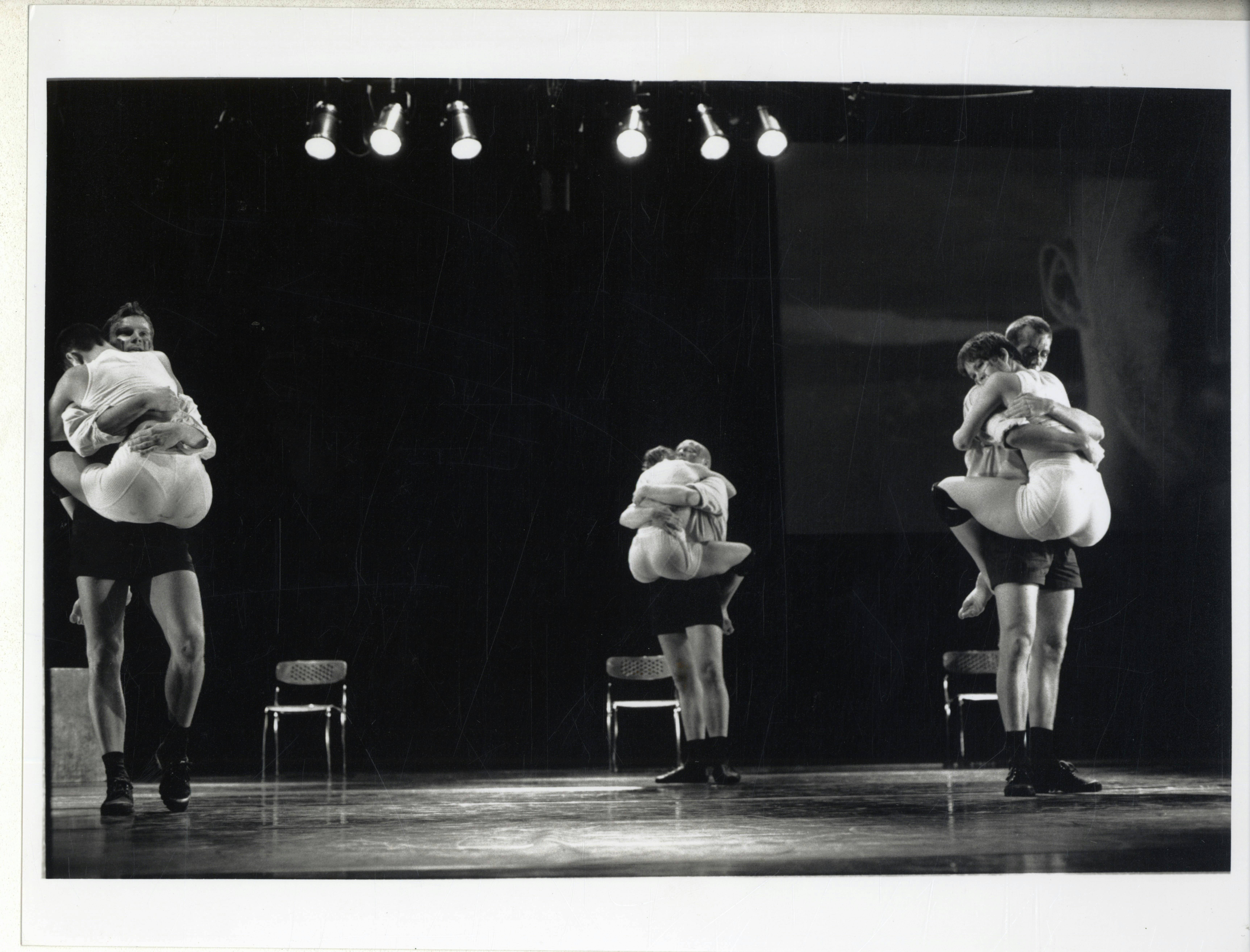 Three couples and three chairs. In front of each chair, a ballerina is clinging to a ballerino in embrace.