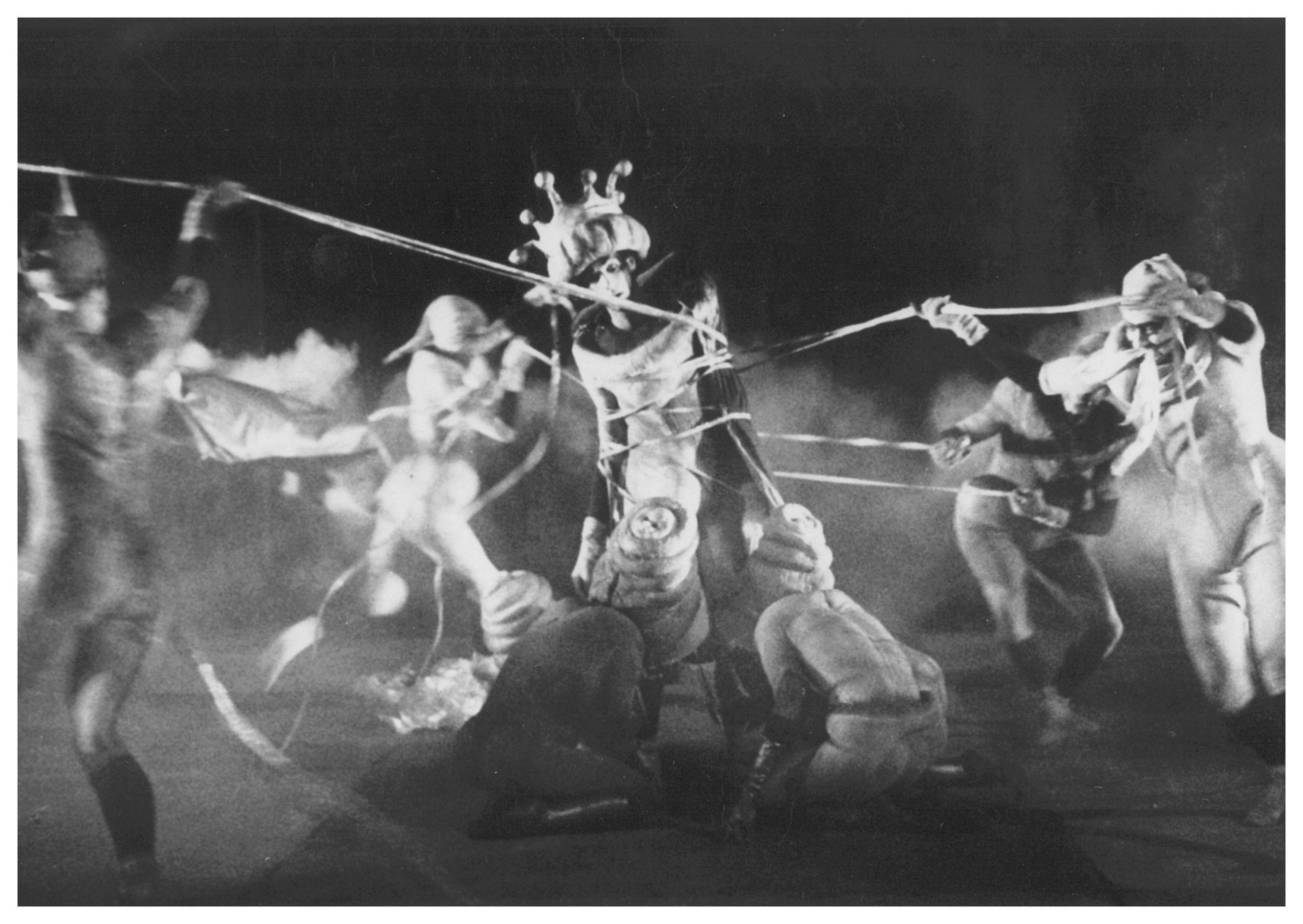 A dominant figure placed in the center, surrounded by several other figures blocking it with strings.
