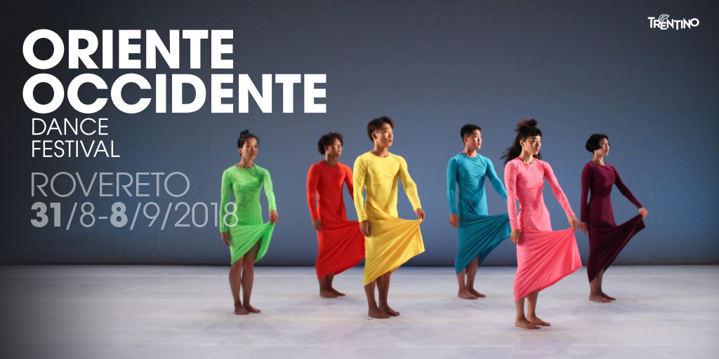 Lavoro grafico del Festival: testi bianchi (Oriente Occidente Dance Festival), sei persone in piedi sollevano un lembo del loro vestito colorato. Lo sfondo è chiaro in terra, e sui toni del blu-grigio alle spalle delle figure.