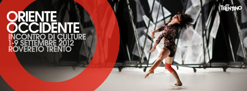 Lavoro grafico del Festival: testi bianchi (Oriente Occidente), una grande O rossa, a destra una danzatrice su palco con dei pannelli sullo sfondo.