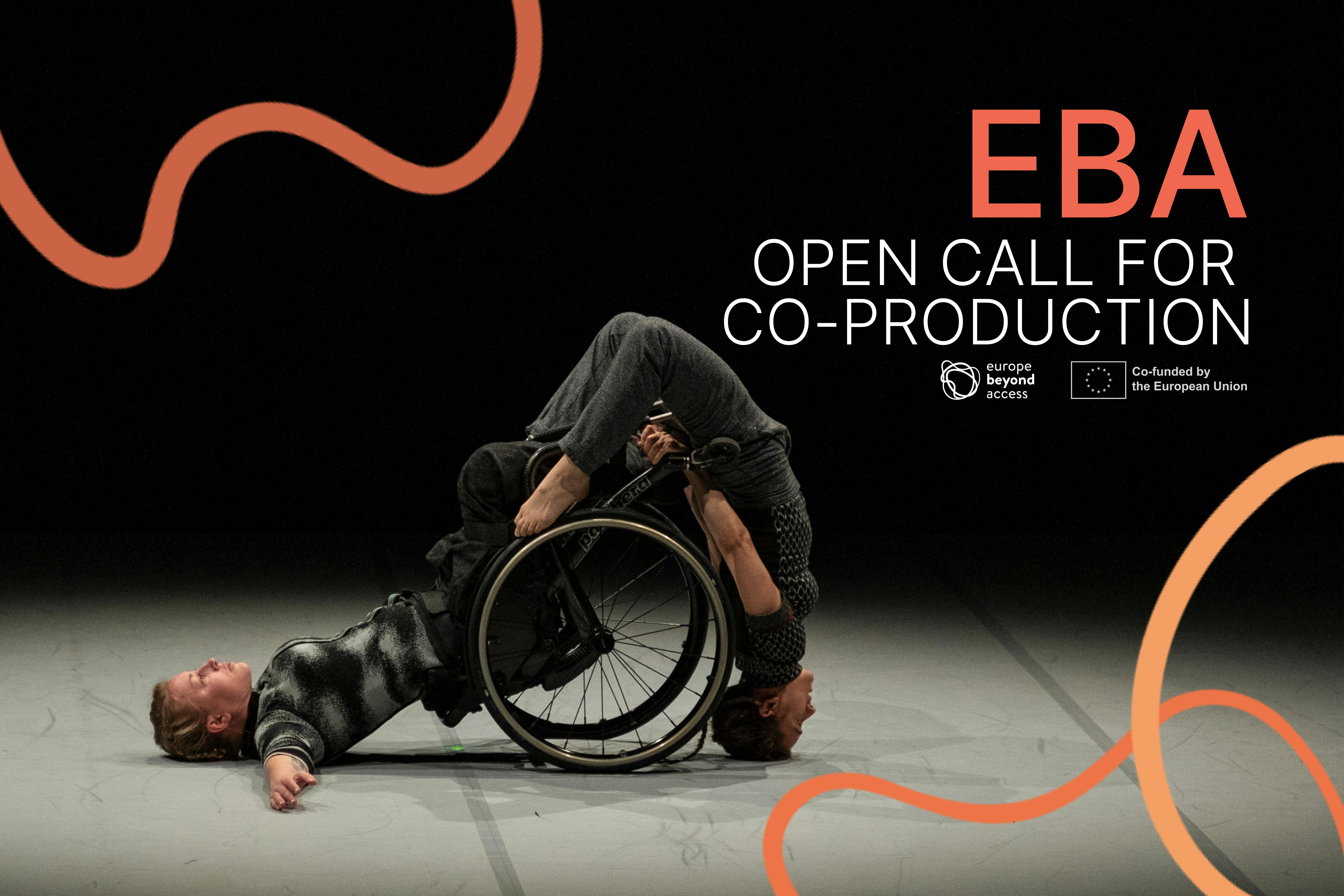 A female wheelchair-using dancer rests on her back. Another female dancer balances on her head using the wheelchair for support - her back arched over the wheelchair