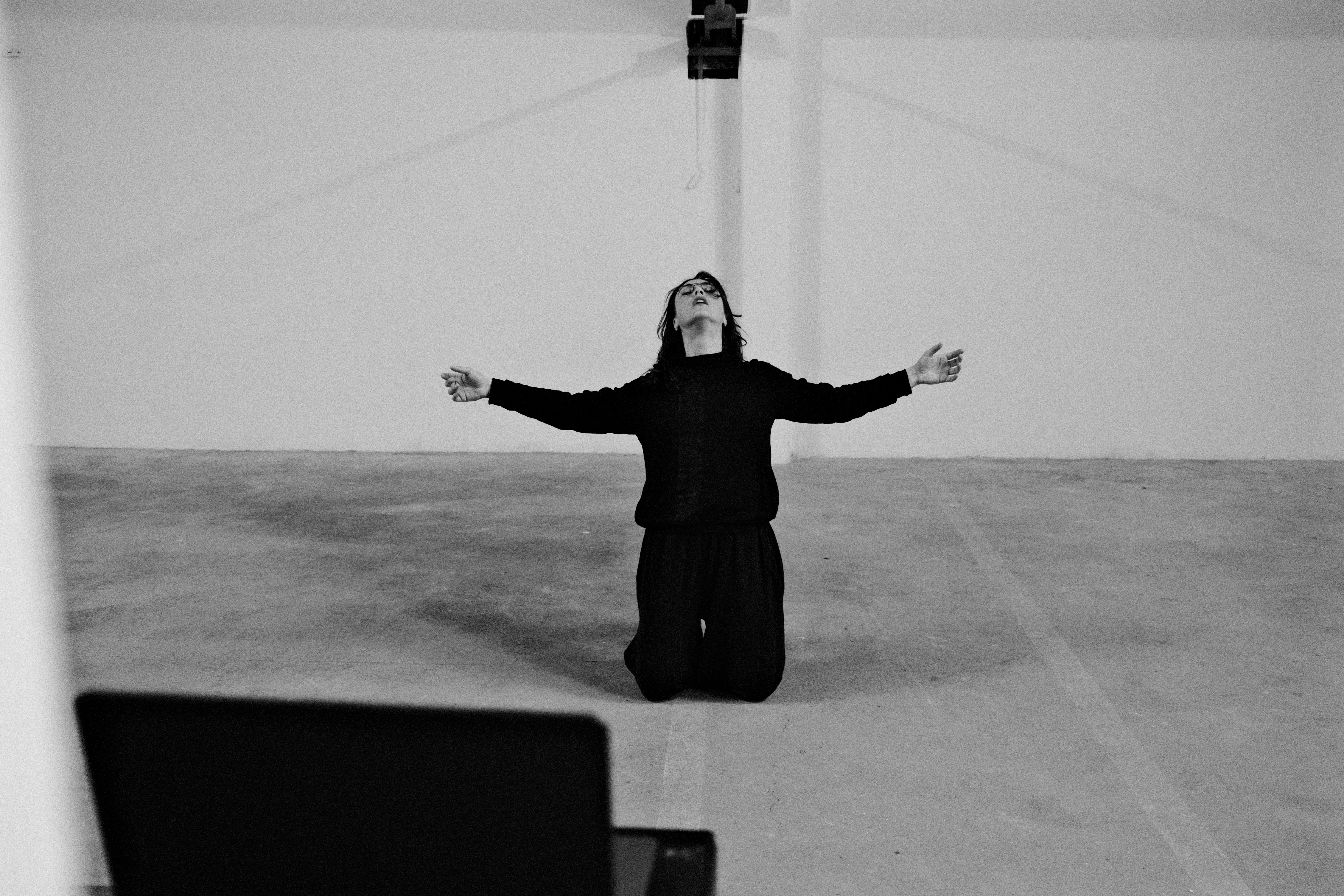 Foto in bianco e nero di una donna inginocchiata con le braccia aperte rivolte verso l'alto
