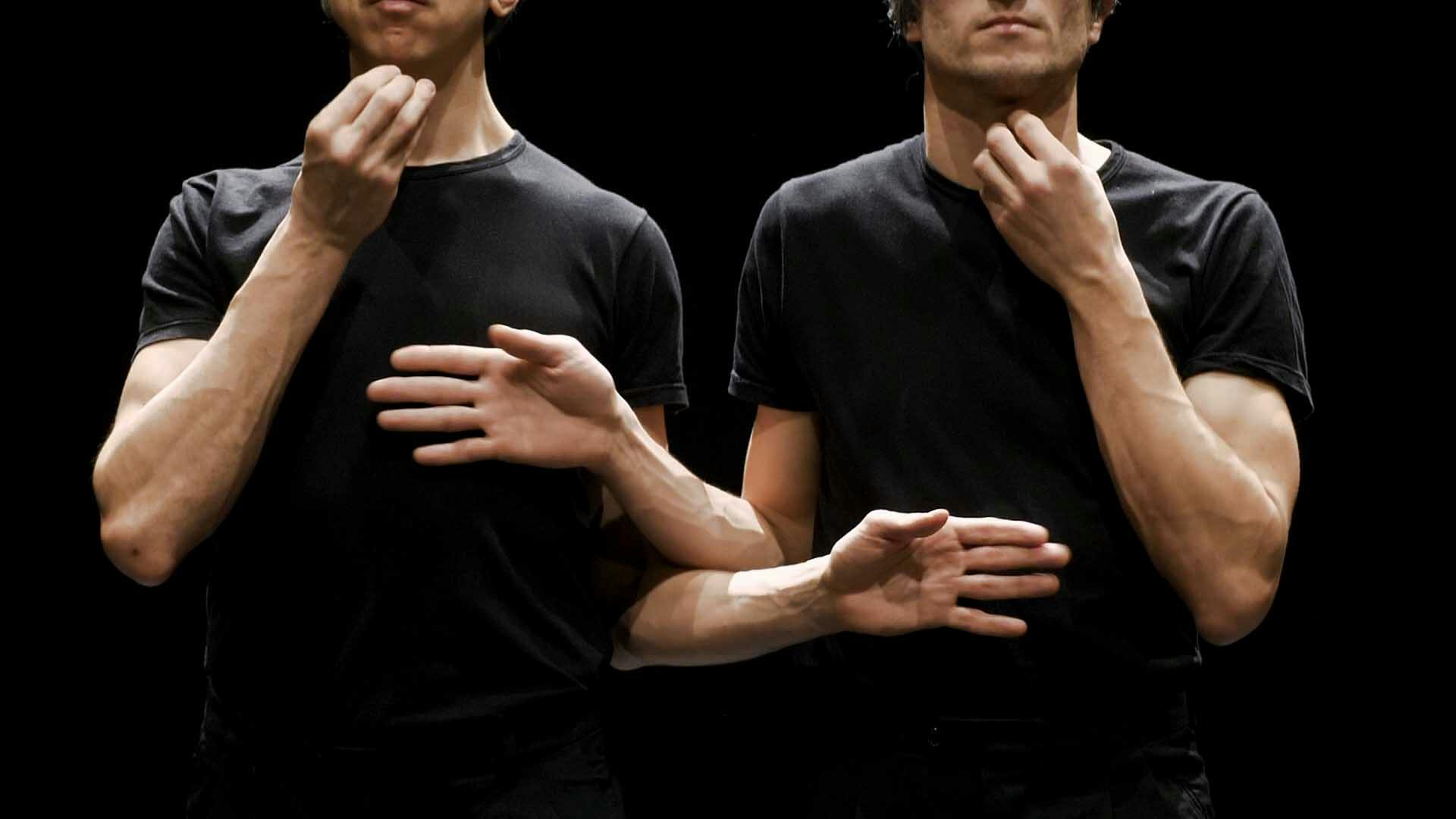 La foto inquadra il busto di due danzatori in piedi uno accanto all'altro.