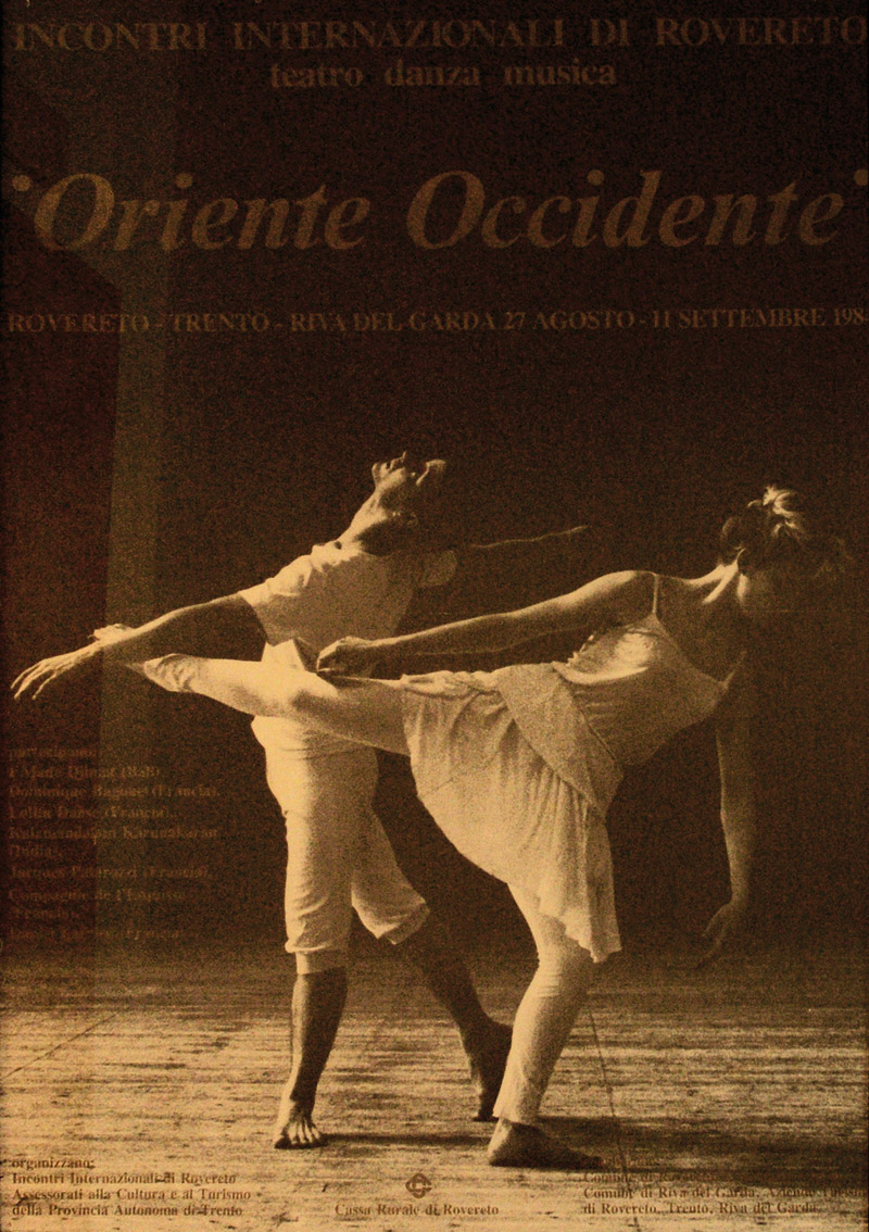 Lavoro grafico del Festival: in primo piano due persone che danzano su un palco, i colori tendono al giallo e le scritte (Oriente Occidente) sono in contrasto con lo sfondo più scuro.