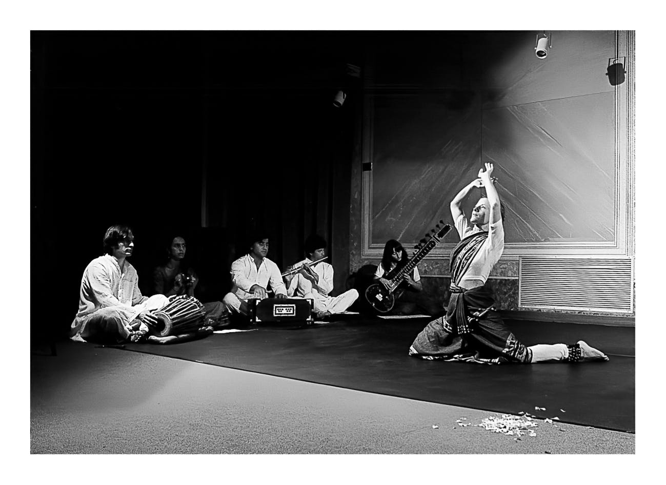 sei persone, di cui cinque musicisti seduti per terra e un danzatore