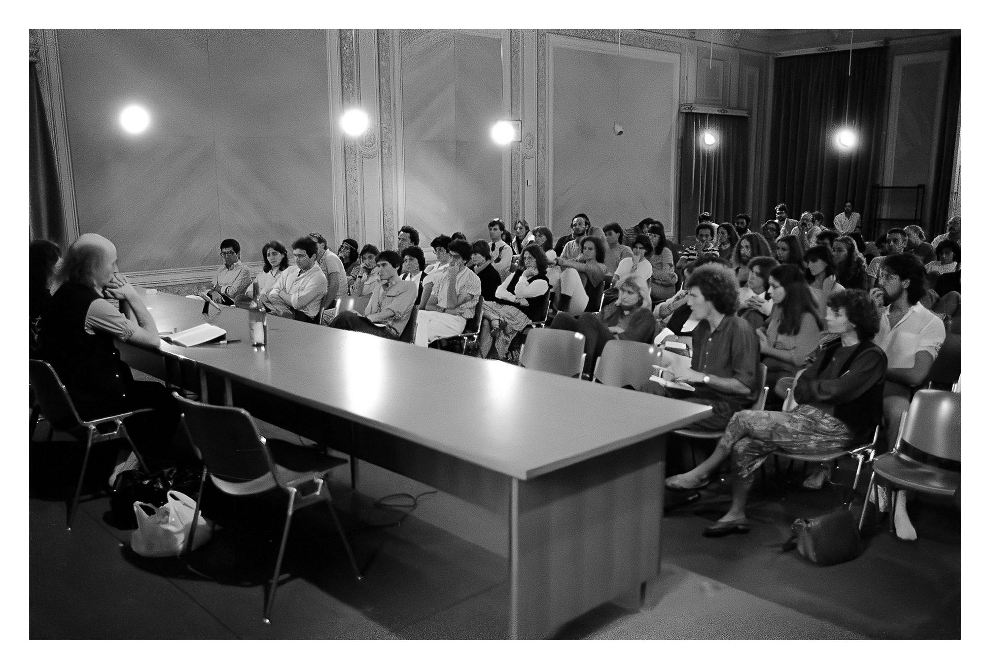 Sala conferenza gremita di persone sedute in ascolto, sul palco due persone, un uomo e una donna