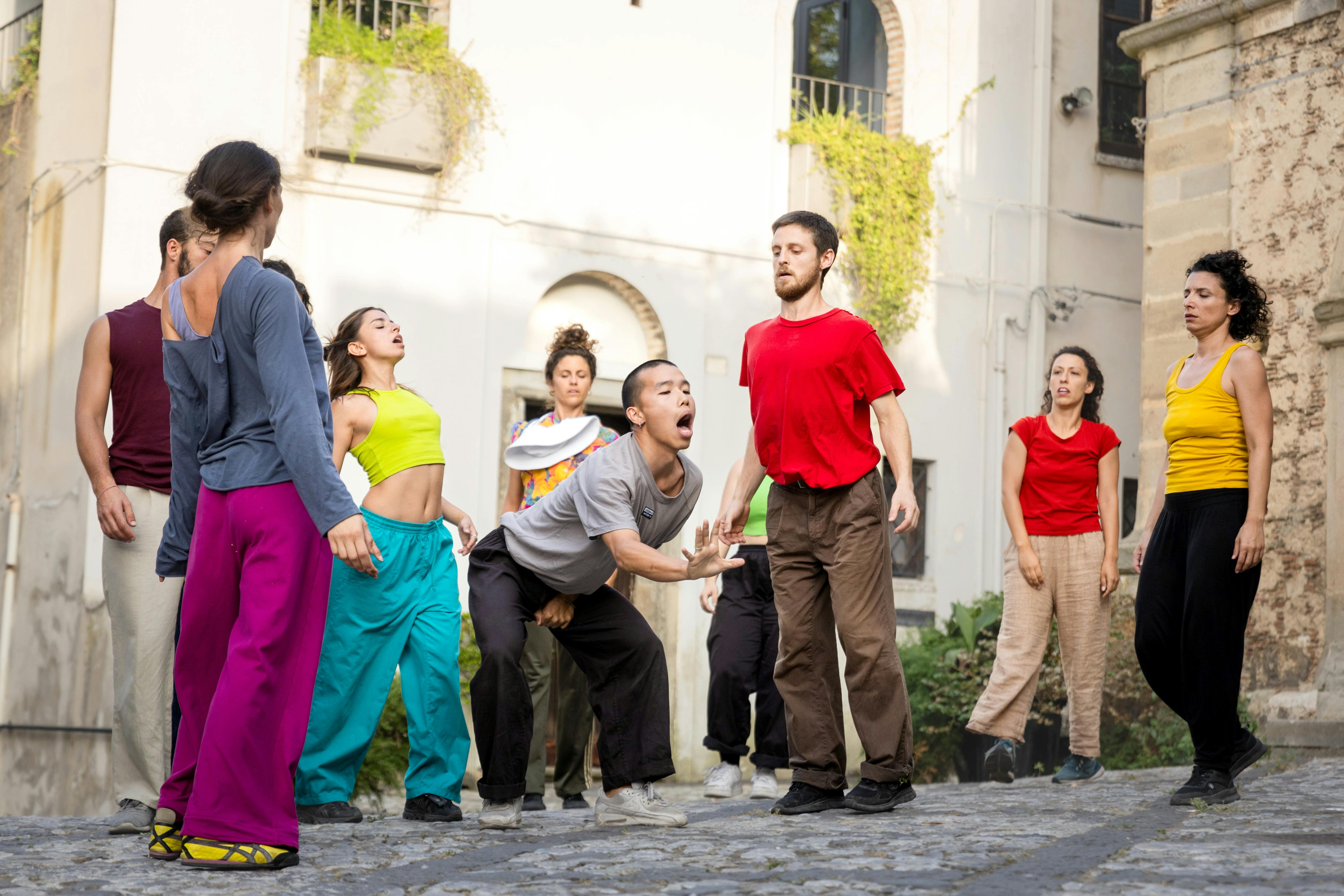 Alcuni ragazzi e ragazze ballano all'aperto ed indossano vestiti colorati