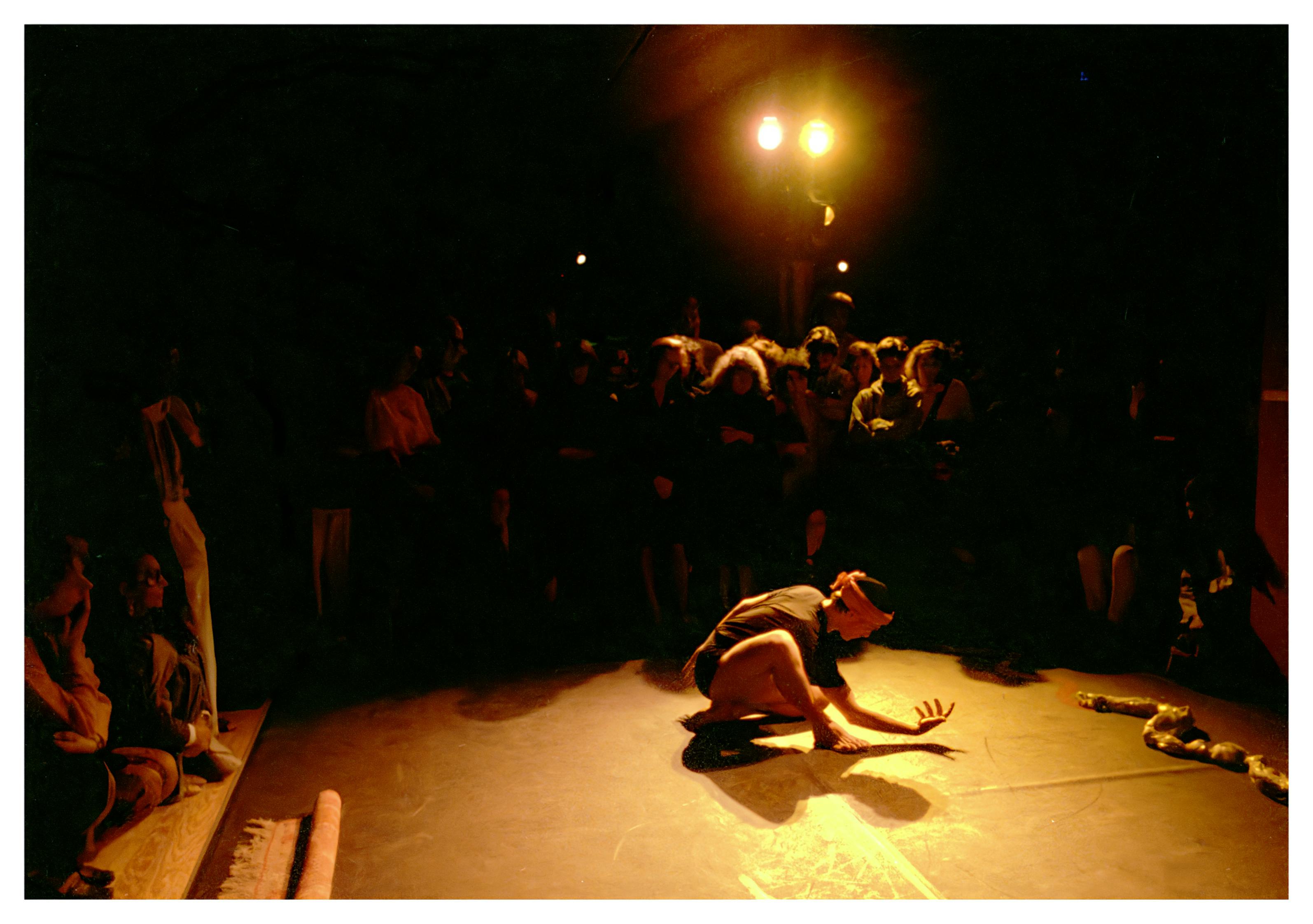 n actor is crouched on the ground. Around him, a standing crowd is watching.