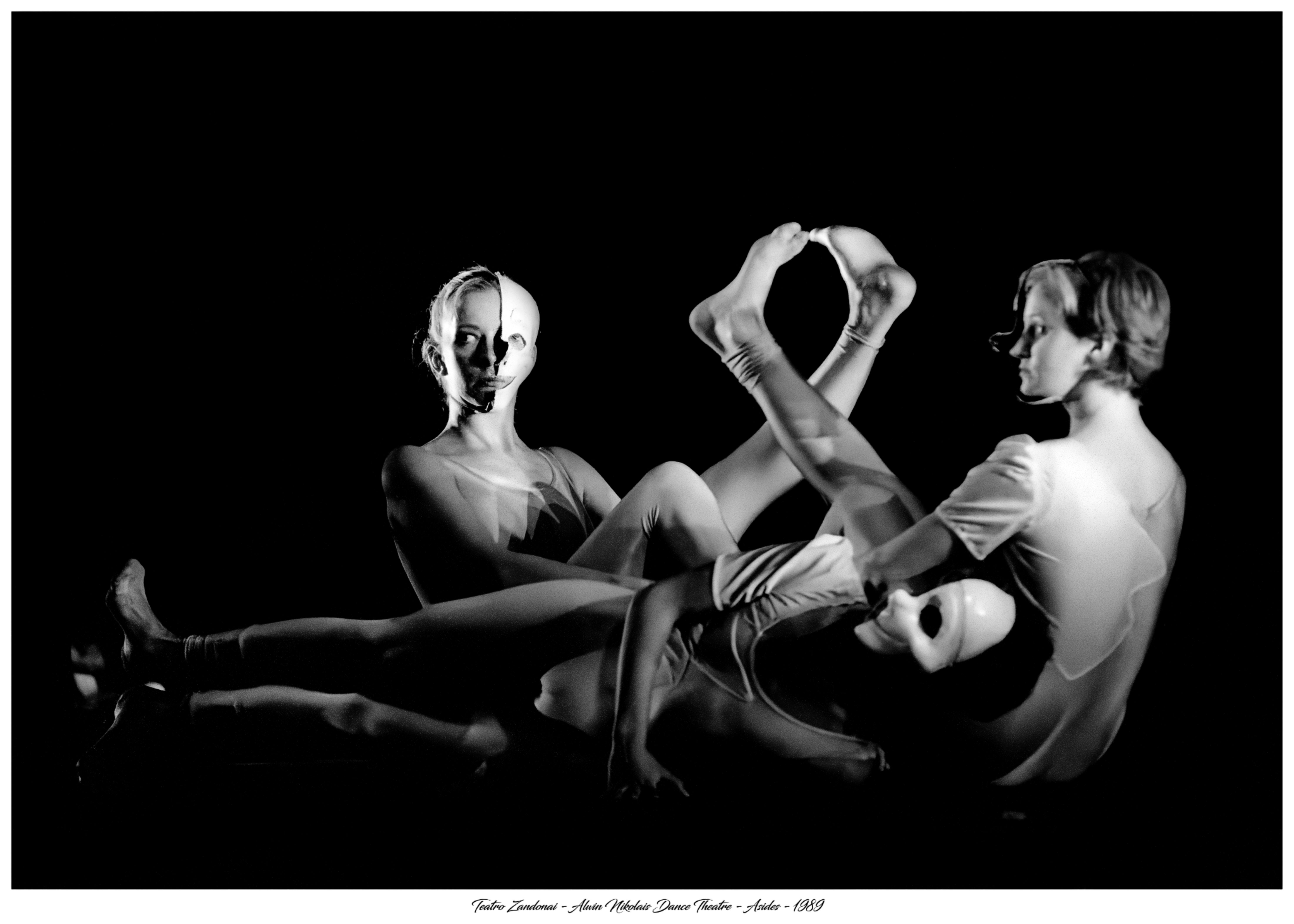Three people, one lying down and two sitting. The ones sitting are crossing their legs with each other.
