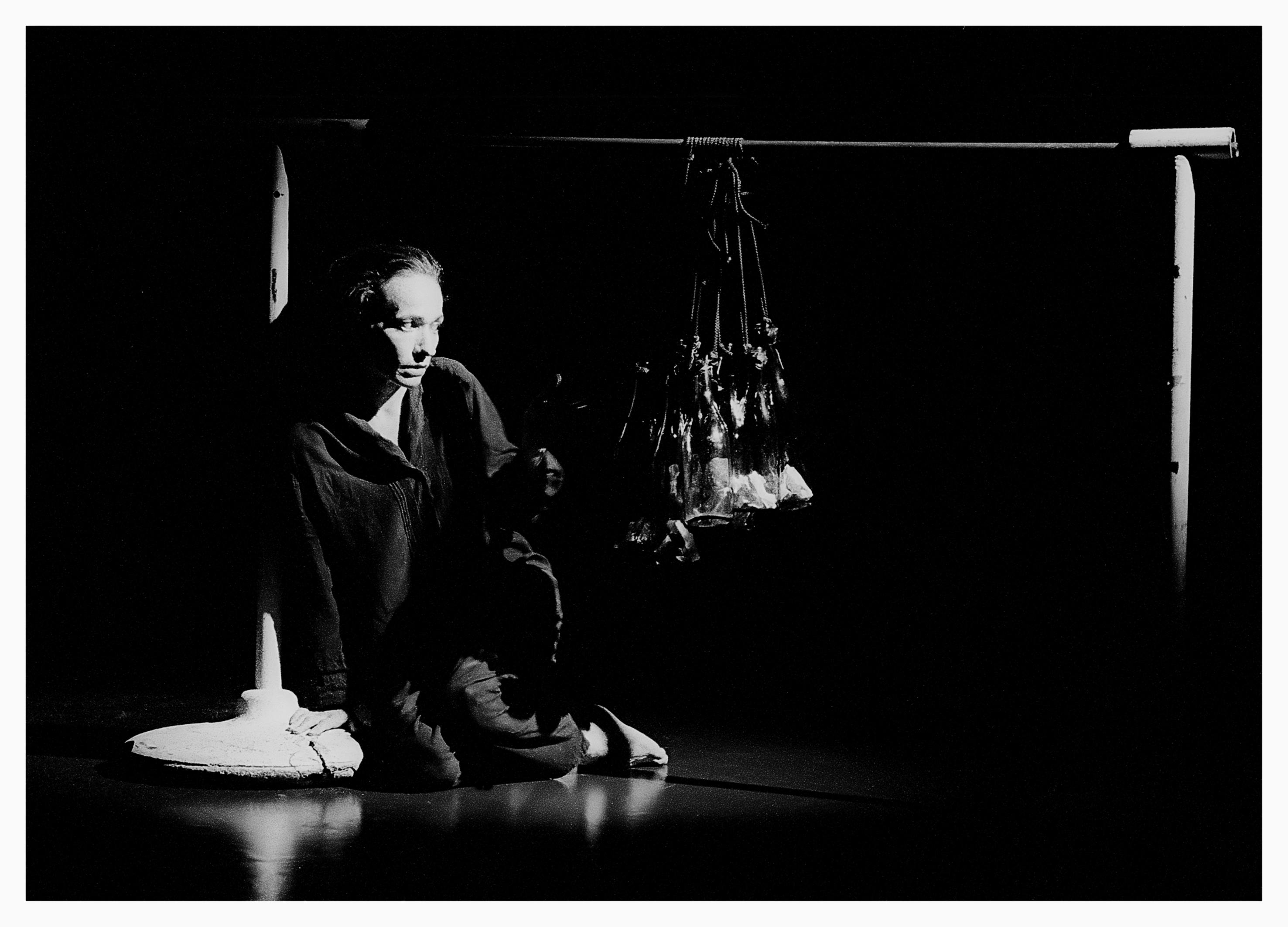 artista in ginocchio che guarda degli oggetti appesi