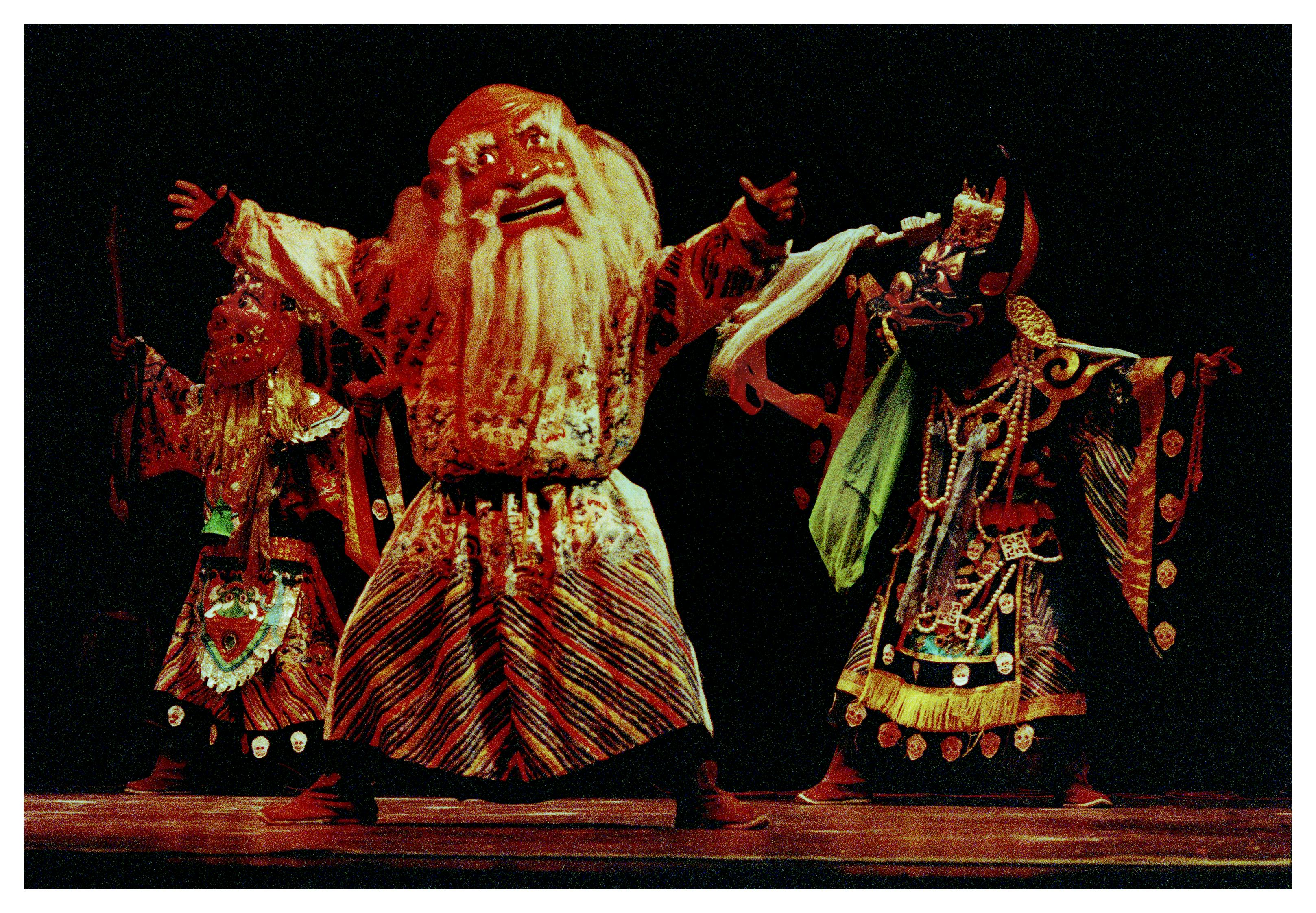 Three people dressed in large masks and very colorful costumes.