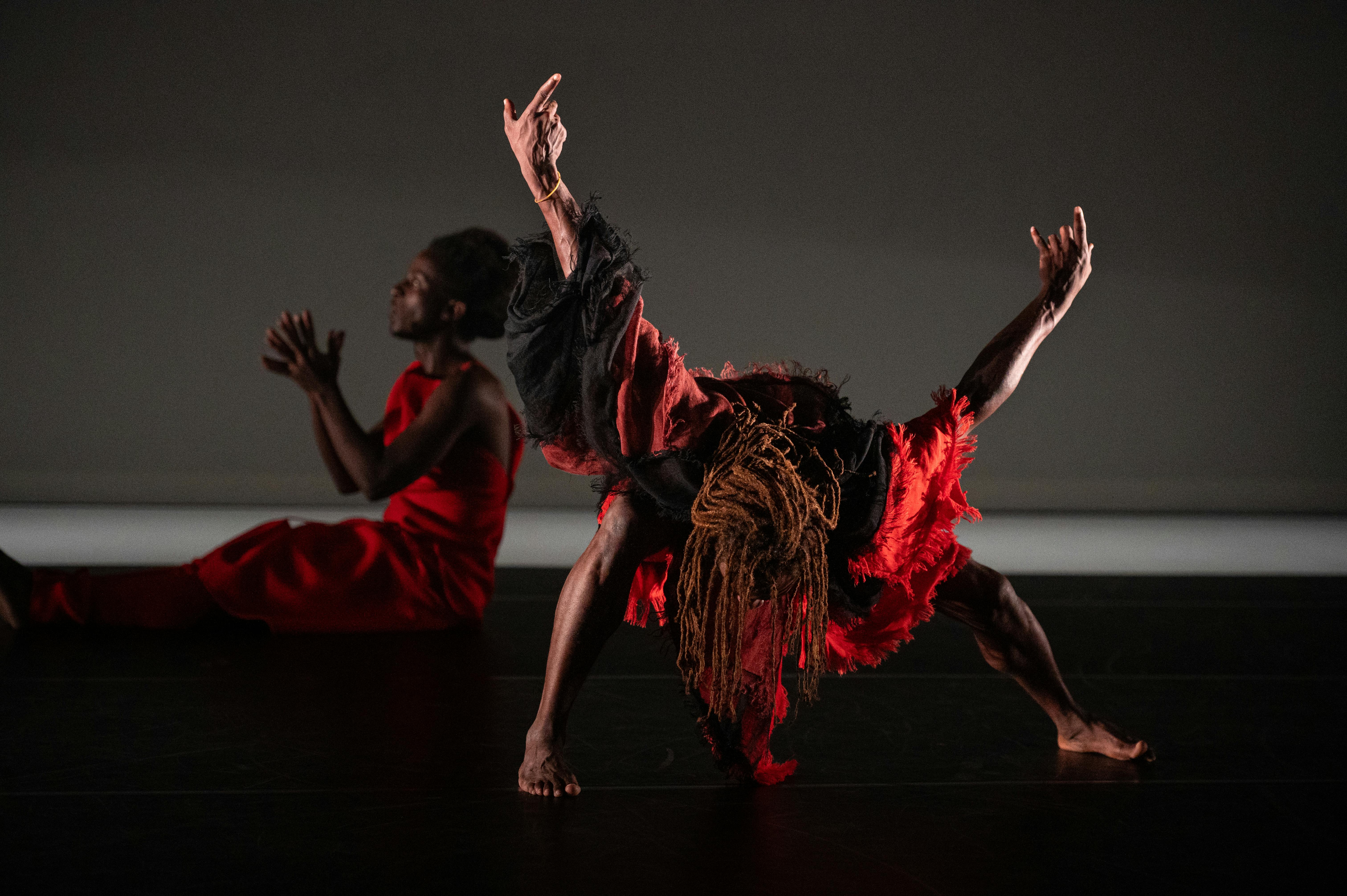 A dancer dances by bending with his arms overhead