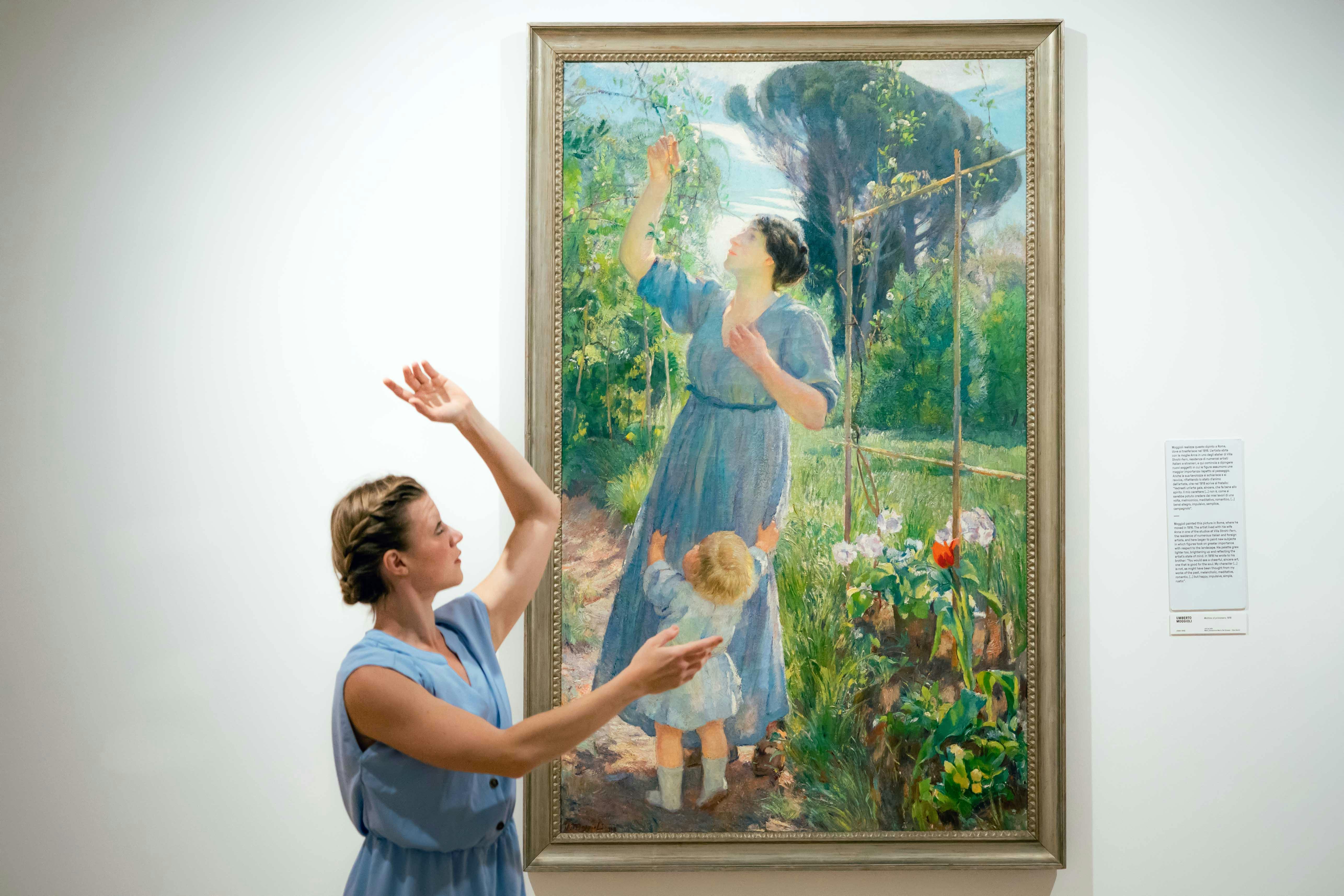 Una danzatrice balla davanti ad un quadro imitando l'immagine dipinta: una donna vestita di azzurro che tiene le braccia in alto
