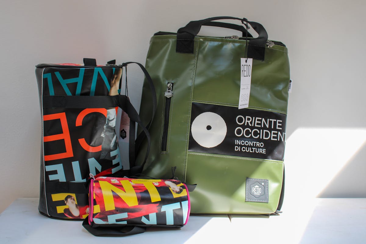 Green backpack, pencil case and small colourful bag made by Redo from last year's Festival communication materials