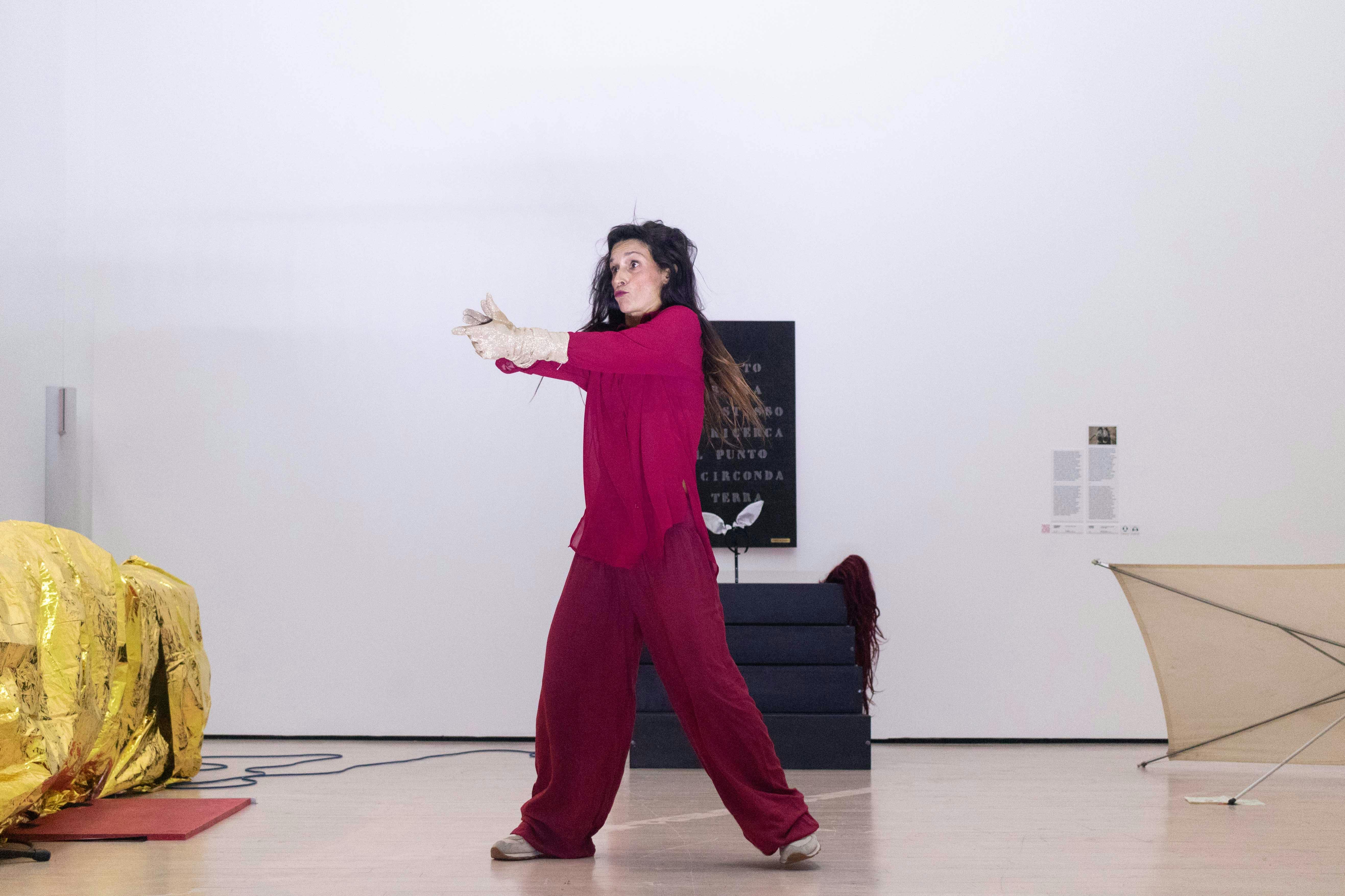 Una performer vestita di viola sta danzando in una sala del museo Mart