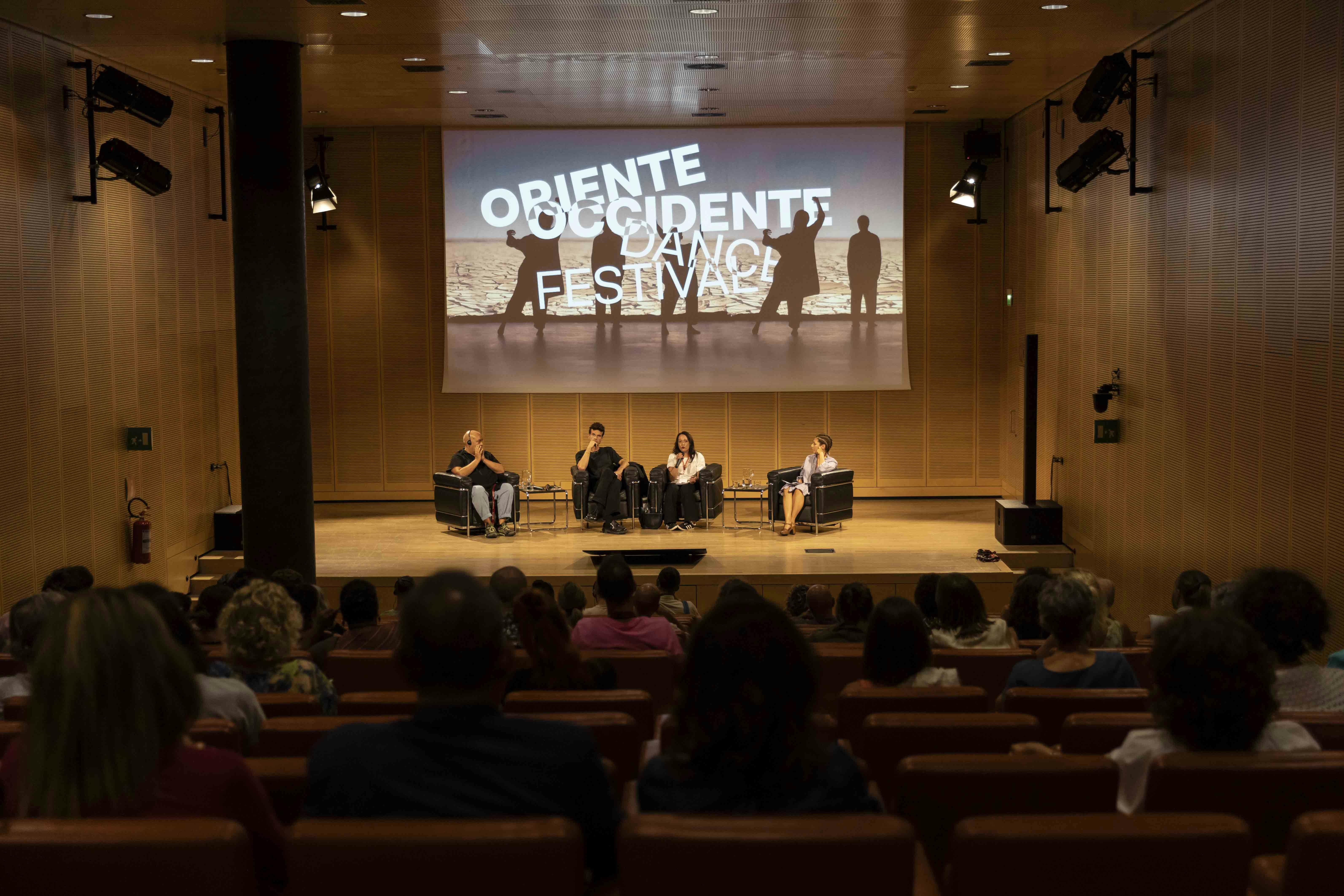 Foto del palco con Thomas Lebrun, Ivan Olita, Maria Carolina Vesce e Susanna Caldonazzi. Vesce sta parlando al microfono.