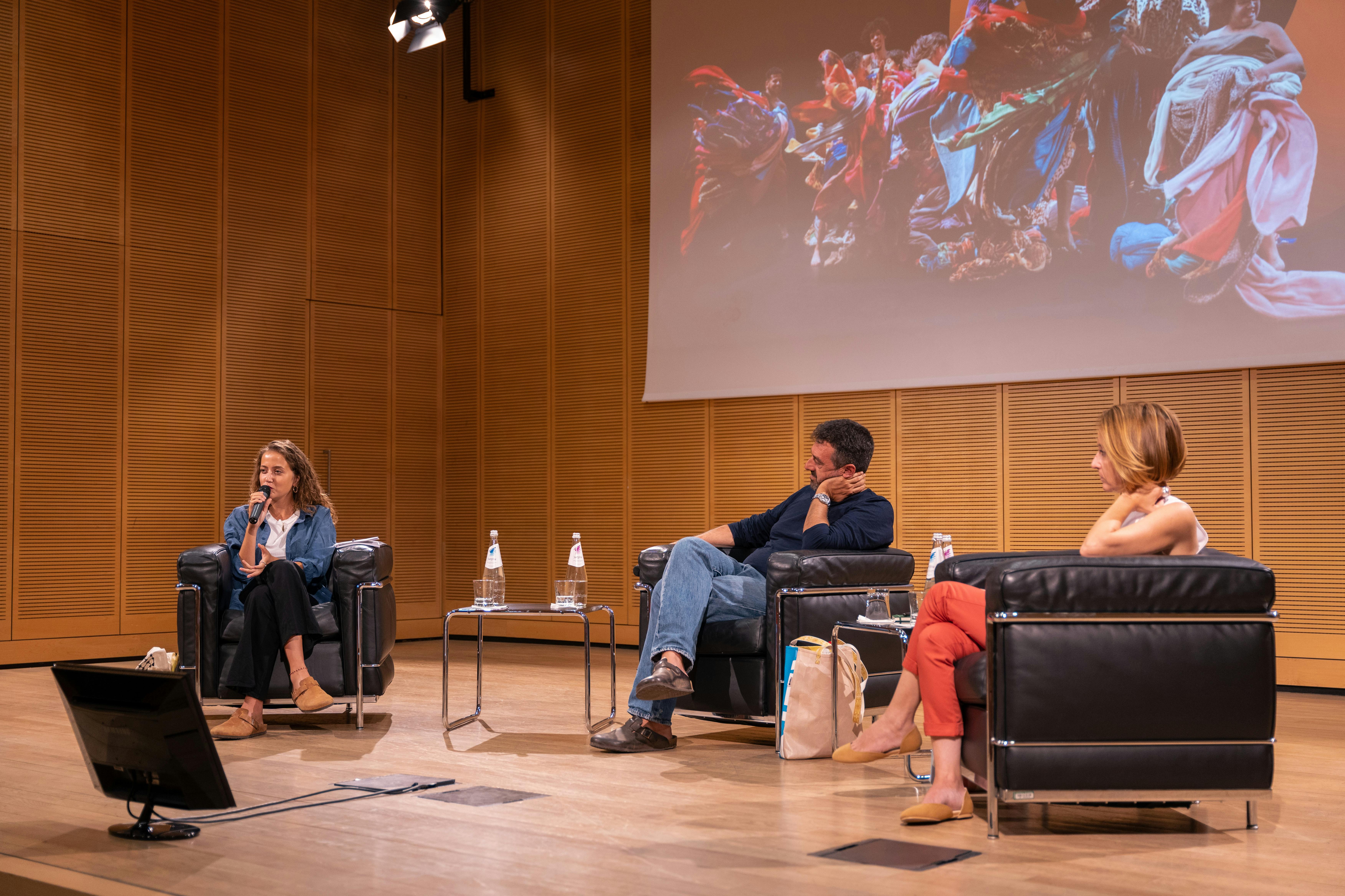 Foto di Christian Elia, Jamila e Silvia Moresi sul palco durante una conferenza. Sono seduti su delle poltrone.